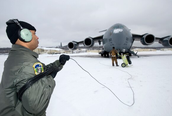 Staff Sgt. Bryan Amaya, a C-17 Globemaster III loadmaster from the 517th Airlift Squadron, wraps up a communication cord after monitoring engine start up before a training mission. The training mission included dropping Army Airborne Soldiers from Fort Richardson, Alaska, and conducting air drops of training bundles that simulate the Soldier's equipment. (U.S. Air Force photo/Master Sgt. Keith Brown) 
