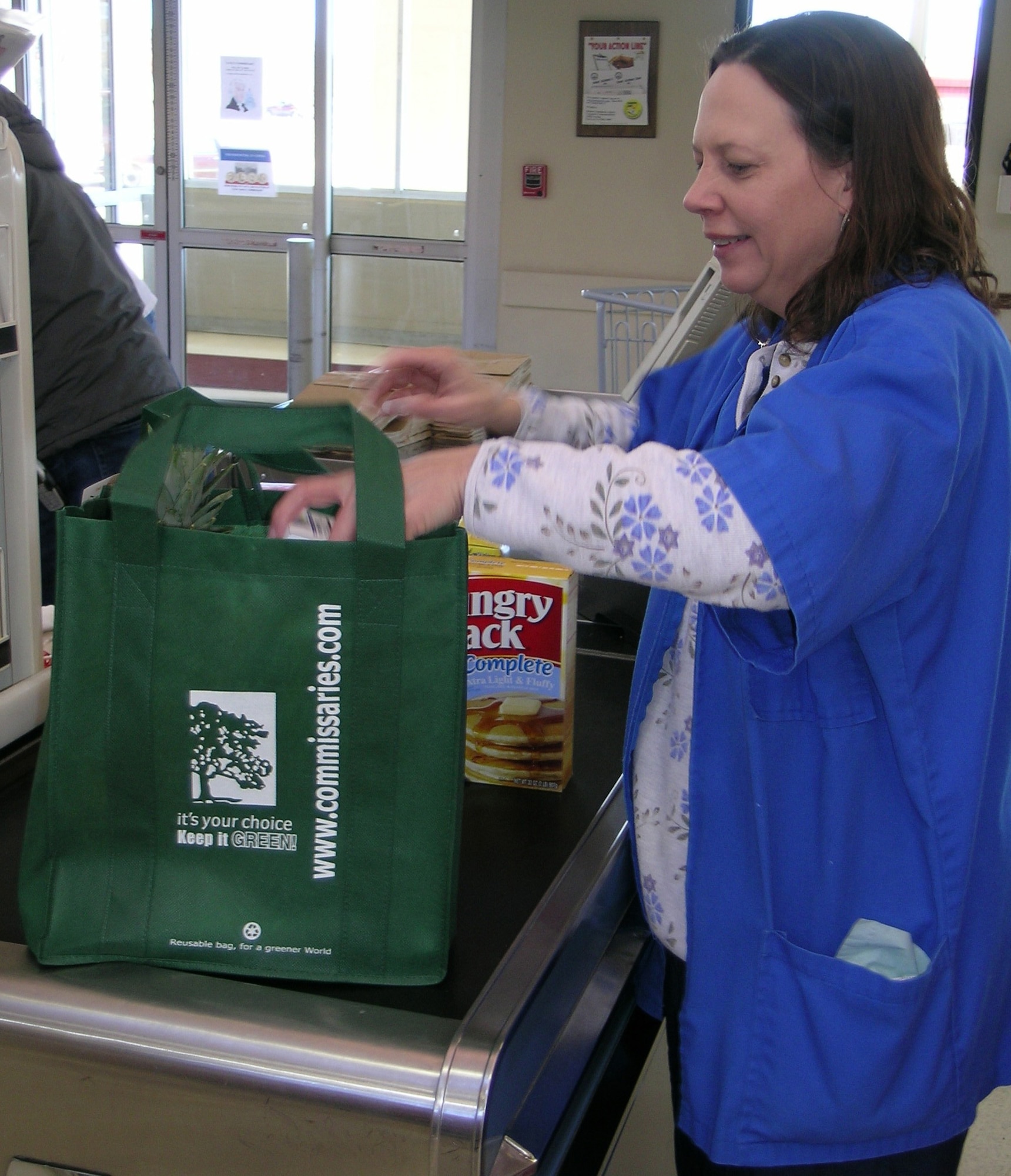 Lisa Pond, Vance Air Force Base commissary store associate, loads a reusable cloth bag with groceries. Customers can use the bags, which hold up to 30 pounds, in place of disposable paper or plastic bags.
