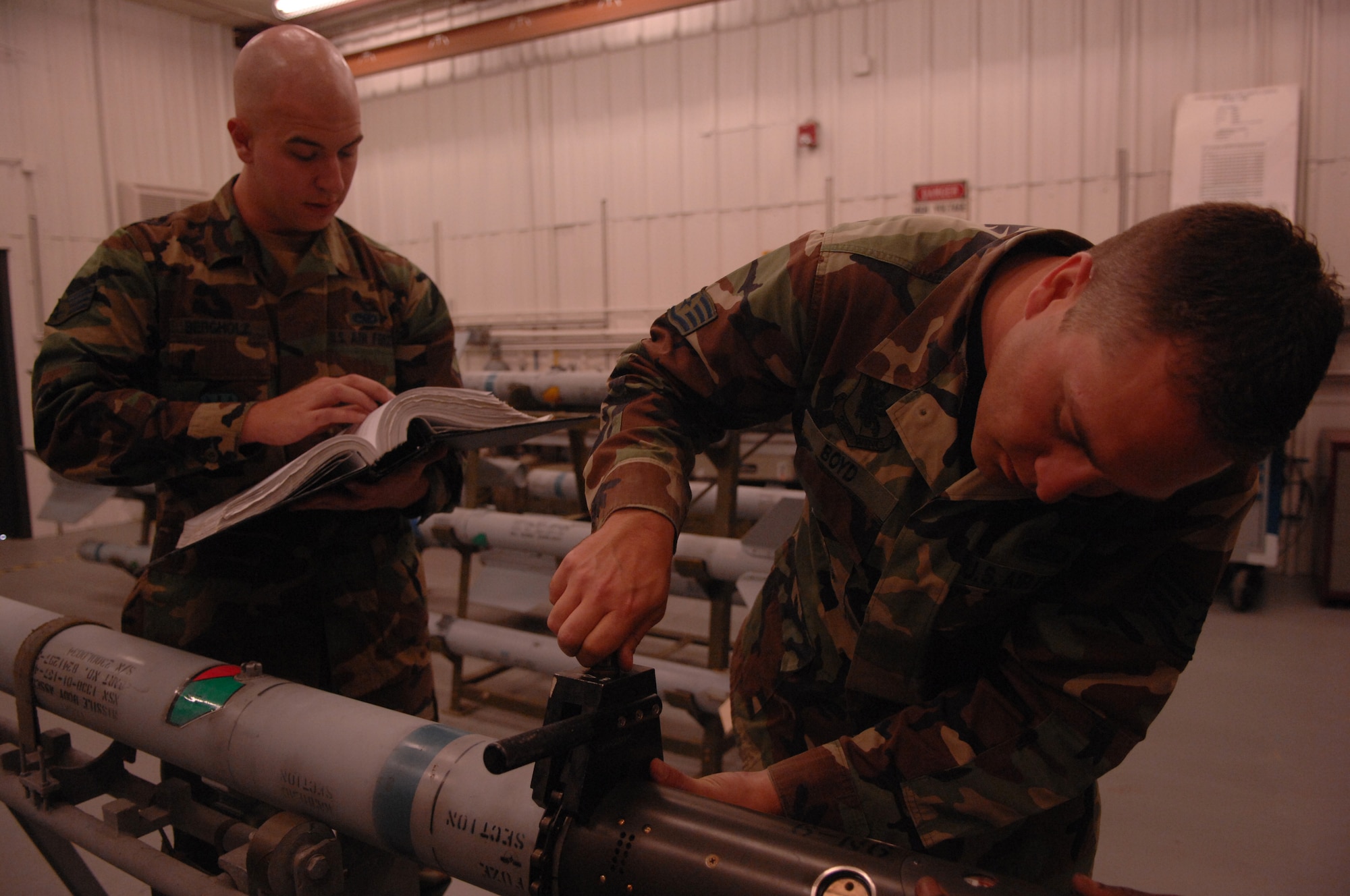 MOODY AIR FORCE BASE, Ga. -- Senior Airman Trevor Bergholz, 23rd Equipment Maintenance Squadron precision guided munitions crew member, reads instructions to Staff Sgt. Stacy Boyd, 23rd EMS precision guided munitions crew chief, as he tightens the coupling ring on an AIM-9 Sidewinder air-to-air training missile Feb. 13 here. The AIM-9 missile is a short-range dogfighting weapon with an active infrared guidance system. (U.S. Air Force photo by Airman 1st Class Gina Chiaverotti)
