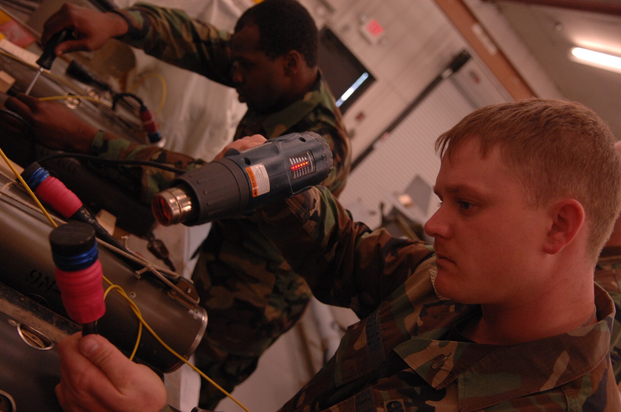 MOODY AIR FORCE BASE, Ga. -- Senior Airman William Ferguson, 23rd Equipment Maintenance Squadron precision guided munitions crew member, heats a shrinking tube on the umbilical connector of a guidance section of a AIM-9 Sidewinder Captive Air Training Missile here Feb. 13 . This plug adapter allows a live seeker head to be used on an inert training missile.  (U.S. Air Force photo by Airman 1st Class Gina Chiaverotti)