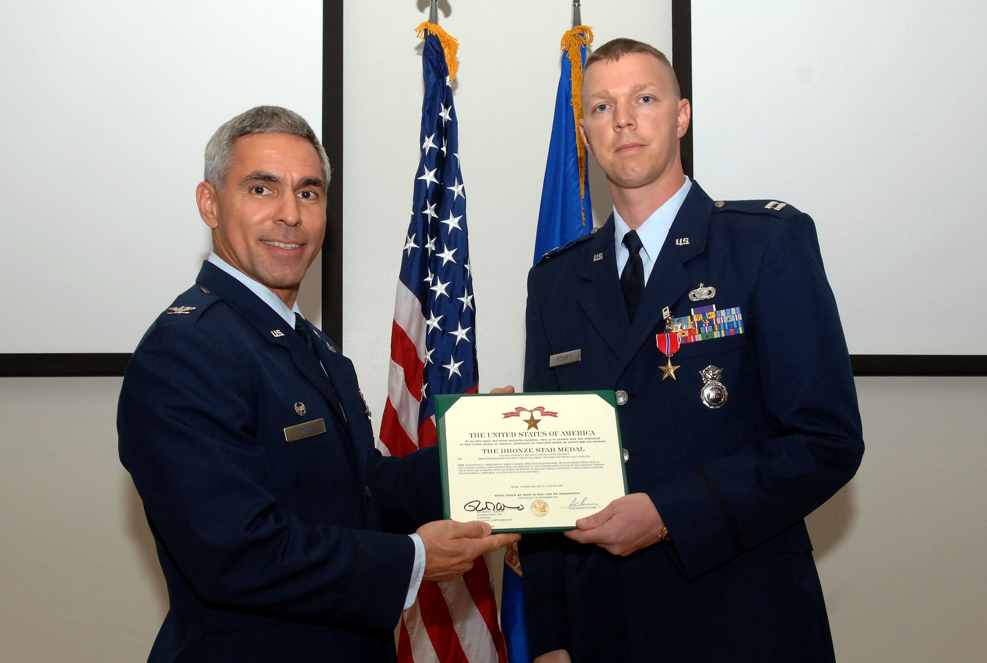 Capt. Anthony McCarty, 15th Security Forces Squadron, receives the Bronze Star from Col. JJ Torres during a Feb. 7 commander's call at the C-17 Ops Building. The Bronze star, the military's eighth highest honor was presented to Captain McCarty for for his outstanding decdication to duty during combat operations at Camp Bucca, Iraq 