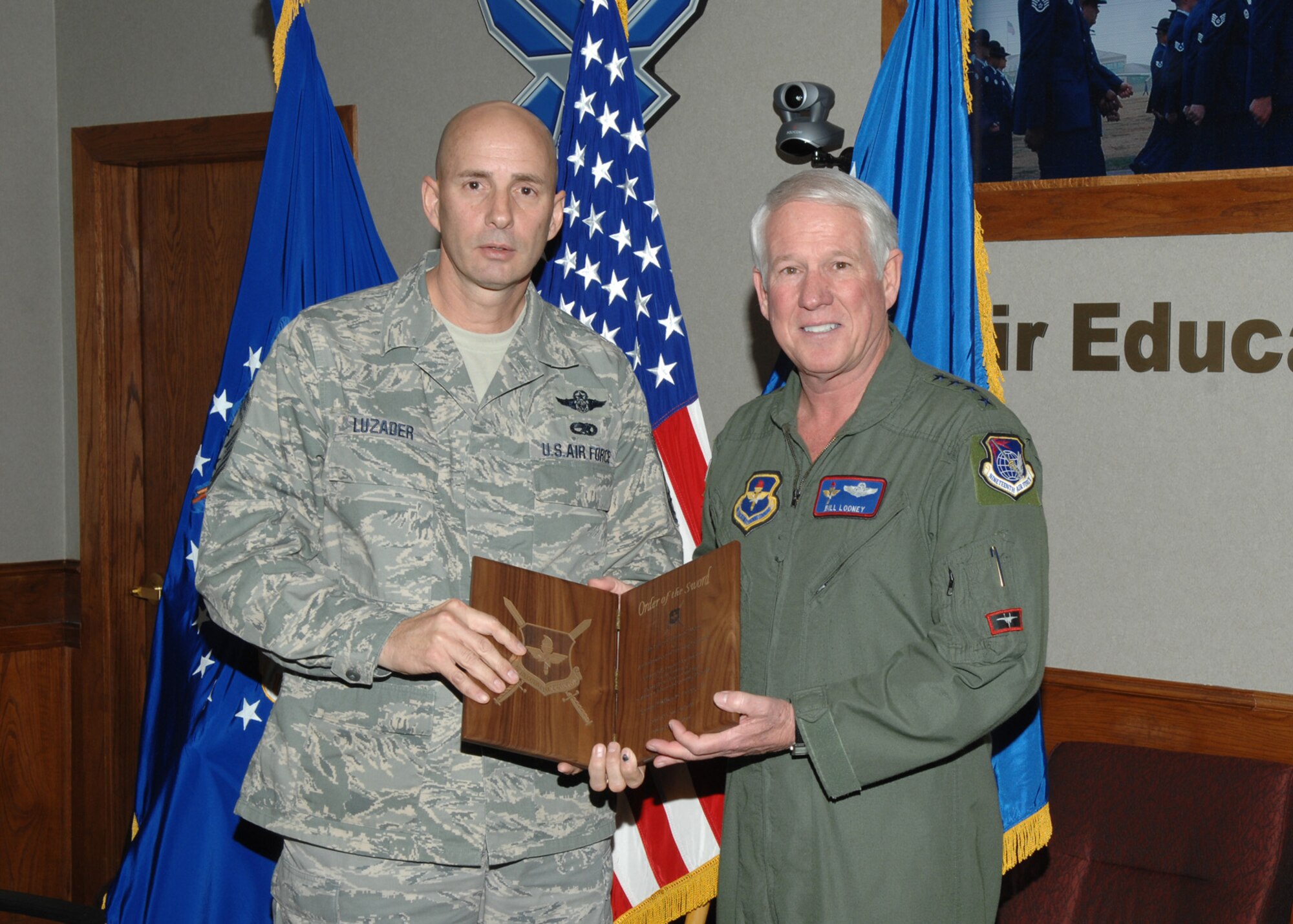 Chief Master Sgt. Mark Luzader, Air Education and Training Command command chief master sergeant, presents Gen. William R. Looney III, AETC commander, an invitation plaque Feb. 13 to receive the Order of the Sword at a ceremony May 30. (U.S. Air Force photo by Joel Martinez)
