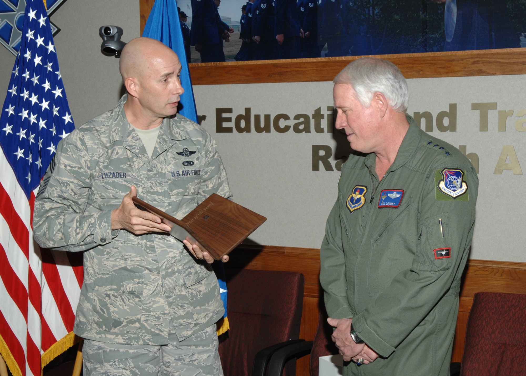 Chief Master Sgt. Mark Luzader, Air Education and Training Command command chief master sergeant, presents Gen. William R. Looney III, AETC commander, an invitation plaque Feb. 13 to receive the Order of the Sword at a ceremony May 30. (U.S. Air Force photo by Joel Martinez)

