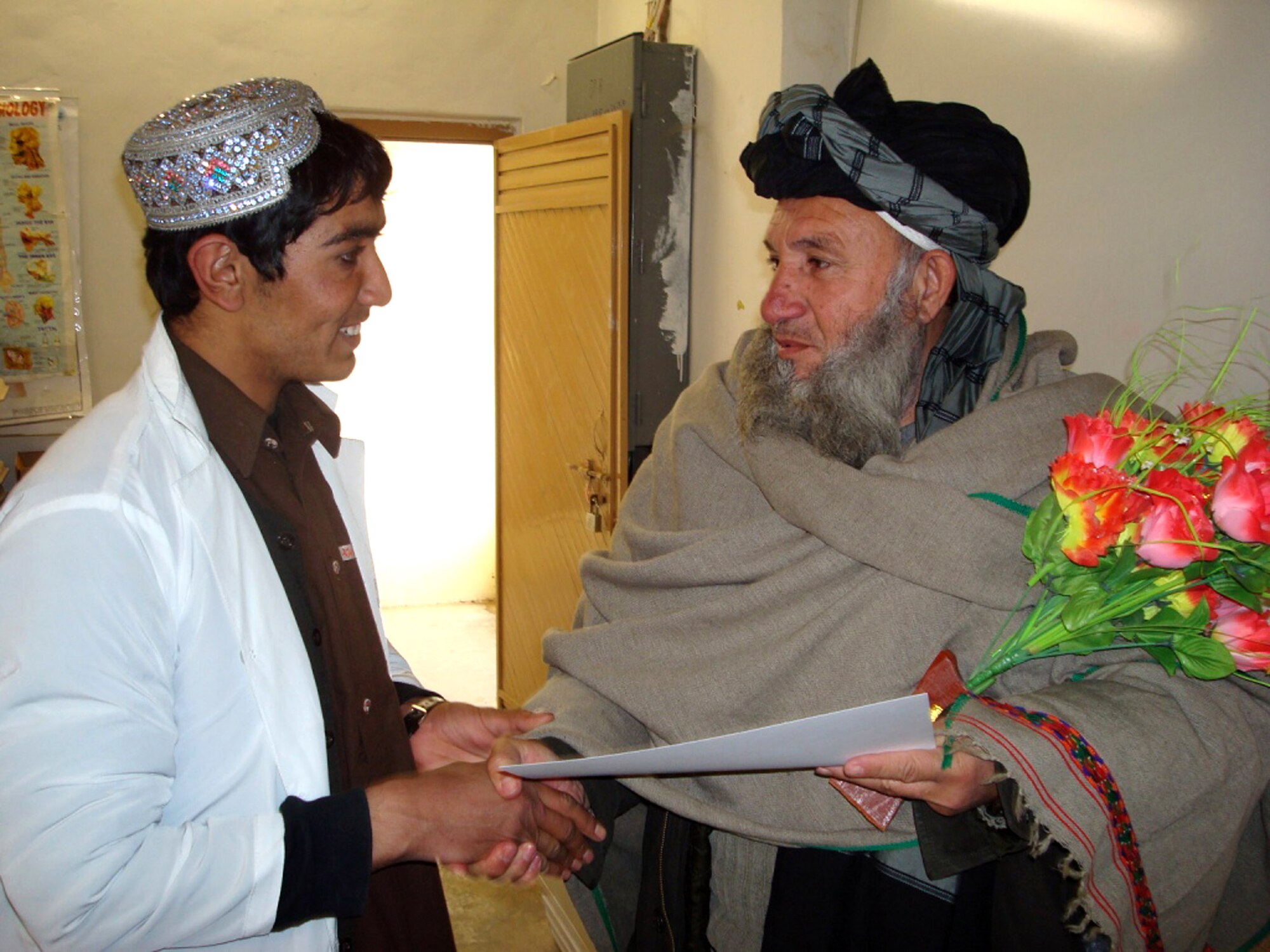 Ahmadullah (left), a graduate of the basic nursing program here accepts his certificate of completion Feb. 5 from Director of Ibn Sina Medical Dr. Fazul Rahman. The 12-month training program-facilitated by the joint Air Force and Army Provincial Reconstruction Team-teaches students the basics of nursing: taking vital signs, assessing overall health, initial patient screening, medical terminology and an overview of medications. The course is taught by a local Afghan employed by the PRT. (U.S. Air Force photo/Capt. Bob Everdeen)