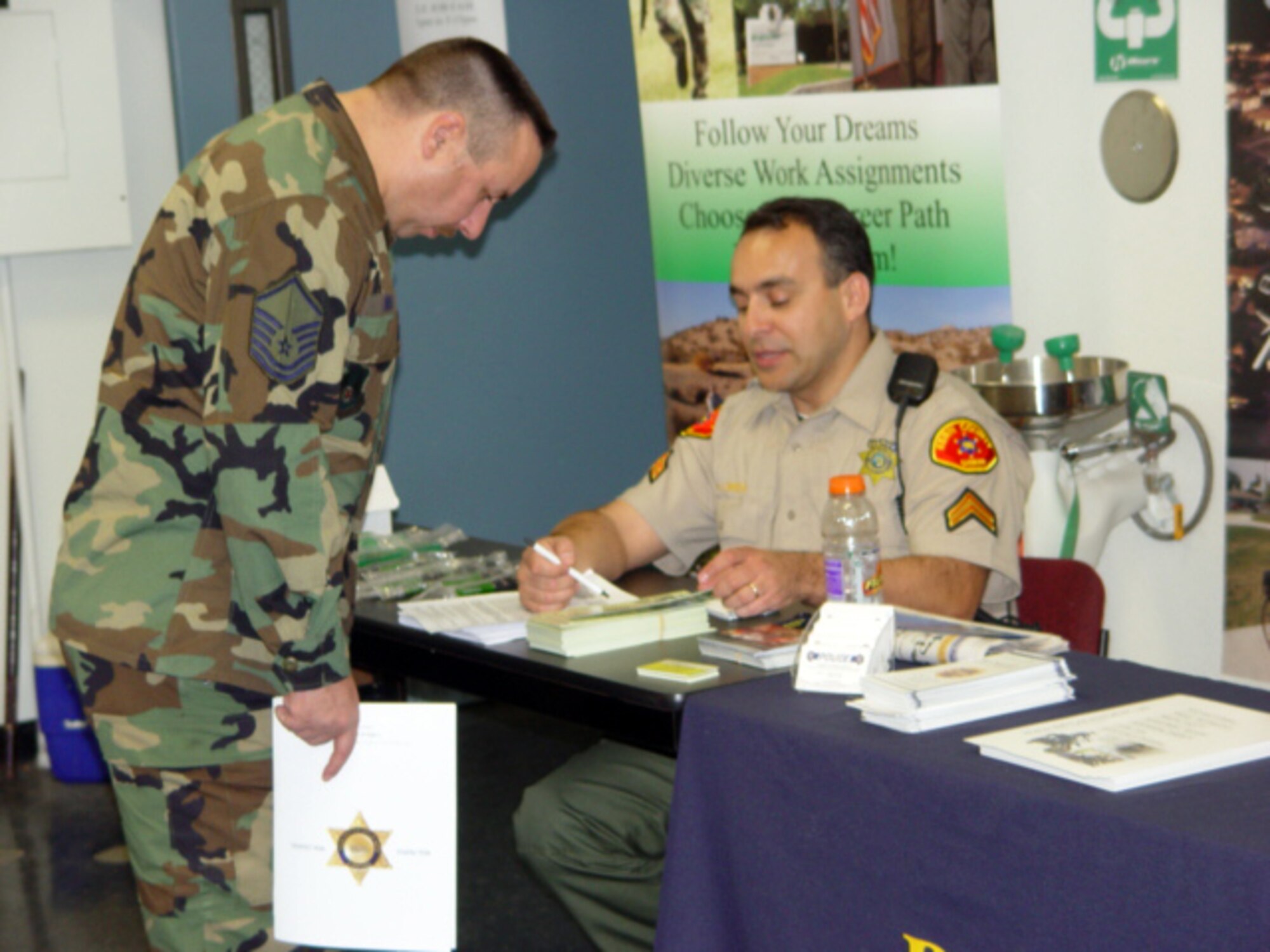 Master Sgt. Thomas Dina (left), 95th Security Forces Squadron operations superintendent, talks to Abel Lomera, Kern County Sheriff's Department senior deputy, during the 95th SFS law enforcement job fair here Feb. 8. (Air Force Photo by Lisa Camplin)