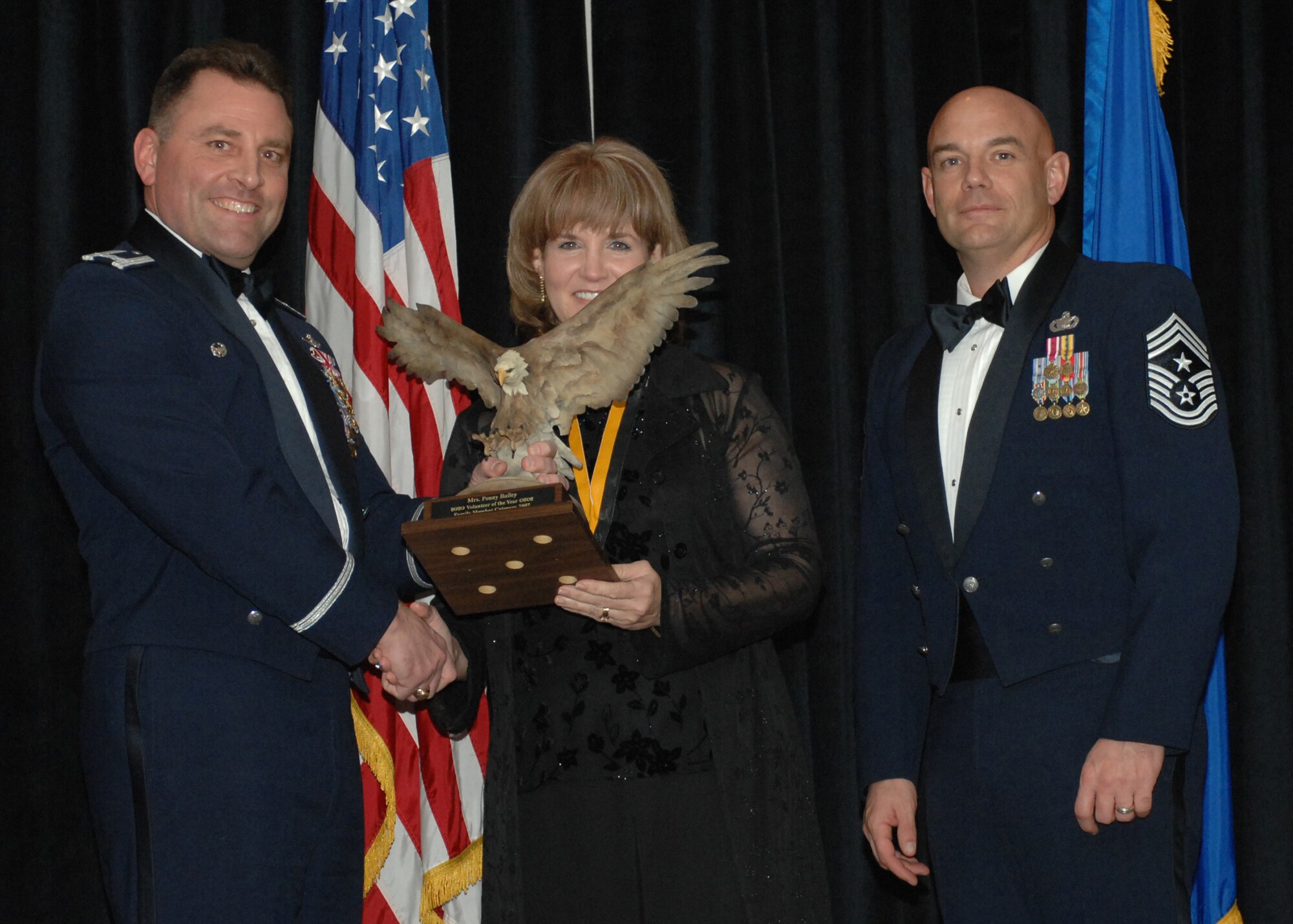 CANNON AIR FORCE BASE, N.M. -- Col.Timothy Leahy (left), 27th Special Operations Wing commander and Chief Master Sgt. Daniel Fischer, wing command chief,  present Penny Bailey with the Family Member Volunteer of the Year award Feb. 9. The annual awards dinner was held at The Landing.  (U.S. Air Force photo by A1C James R. Bell)