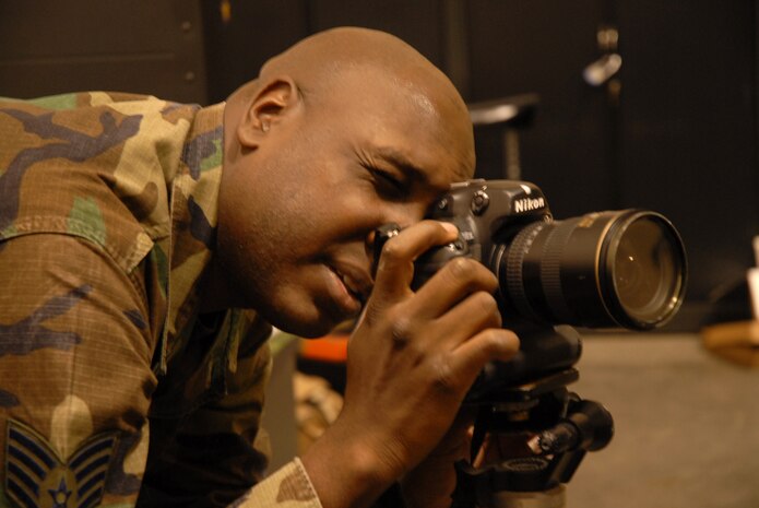 Staff Sgt. Quinton Russ, 1st Combat Camera Squadron combat photographer, adjusts the settings on his camera in preparation for an environmental photo shoot on Charleston AFB Tuesday. (U.S. Air Force photo/Airman 1st Class Melissa White)