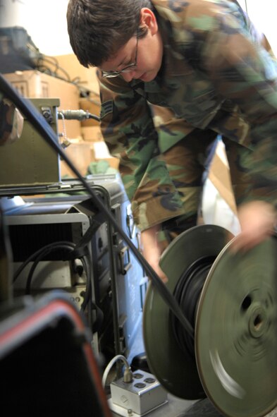 Senior Airman Jenna Saenz, 612 Air Communications Squadron, unwinds cable from a spool in order to perform a preventive maintenance inspection on a URC-119 HF System Feb. 5. Airman Saenz works in the Deployable Radio/Datalinks section of 612th ACOMS (U.S. Air Force photo by Senior Airman Jesse Shipps)