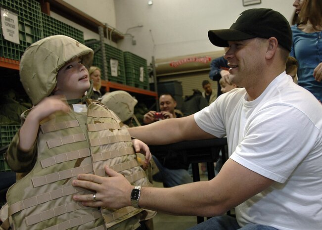 Staff Sgt. Brandon Bennett, 437th Medical Operations Squadron Mental Health Clinic NCO in charge, sizes his stepson, Oliver Heaviside, 6, for a flak jacket at the family deployment line on Charleston AFB Feb. 9.  The family deployment line oriented family members through the deployment process. (U.S. Air Force photo/Airman 1st Class Katie Gieratz)
