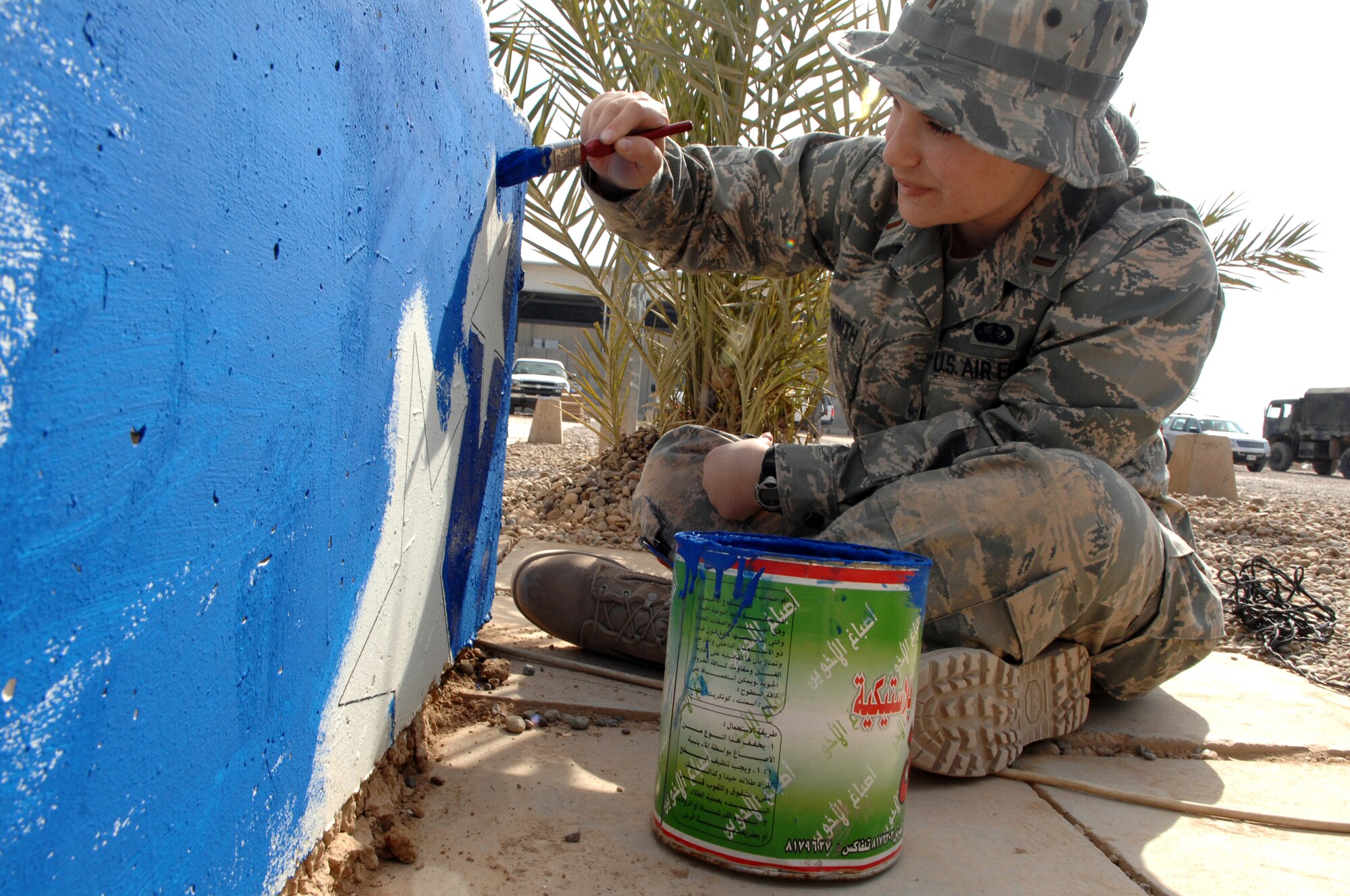 BALAD AIR BASE, Iraq -- 2nd Lt. Elizabeth Goldsmith, 332nd Expeditionary Services Squadron flight commander, paints the T-barrier in front of the United Services Organization prior to its grand opening here, Feb. 6. Many volunteers pitched in to get the finishing touches done the week before the opening of the first USO in Iraq. Liuetenant Goldsmith is deployed from Seymour-Johnson Air Force Base, N.C. (U.S. Air Force photo/ Senior Airman Julianne Showalter)