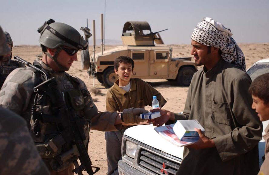 CAMP BUCCA, Iraq – Staff Sgt. Matthew Hamblen distributes schools supplies to an Iraqi man for his younger brothers Feb. 7, 2008. The donation is part of an area-wide effort in near Camp Bucca to aid the surrounding citizens in maintaining their newly returned province. Al-Basra became the ninth province in Iraq to be transitioned to Iraqi provincial control in January. Sergeant Hamblen is deployed from Moody Air Force Base, Ga.  (U.S. Army photo/Spc. Brandon Hubbard, 300th MP BDE)