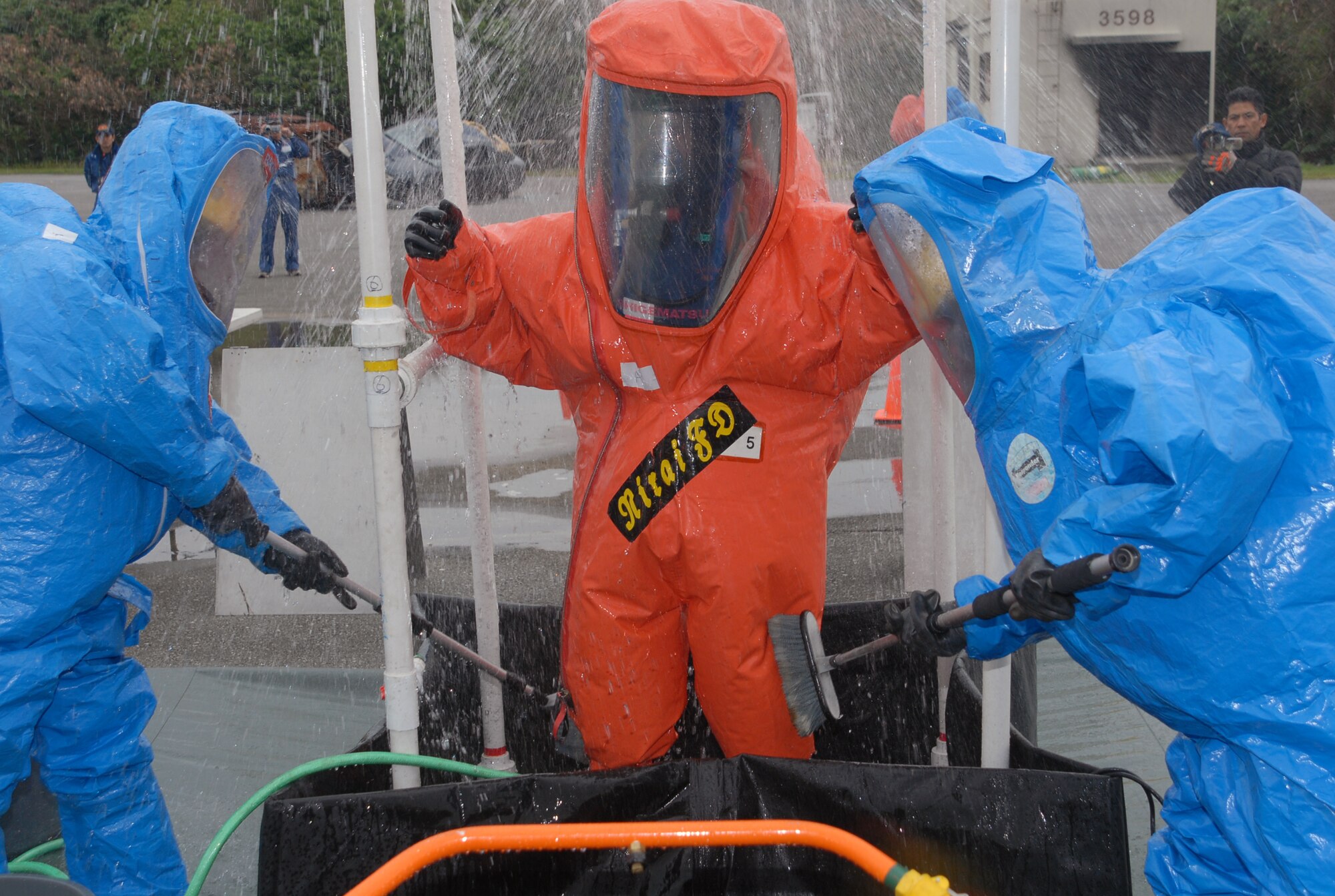 Members of the Kadena Fire Department (blue hazardous material suits) wash off a Nirai firefighter as he transitions out of a simulated chemically contaminated zone during a joint training exercise at Kadena Air Base, Japan, Feb. 14, 2008. These joint training exercises allow Kadena and Nirai fire department personnel to gain further understanding of each other's skills, and foster a better working relationship. (U.S. Air Force photo/Staff Sgt. Christopher Marasky)