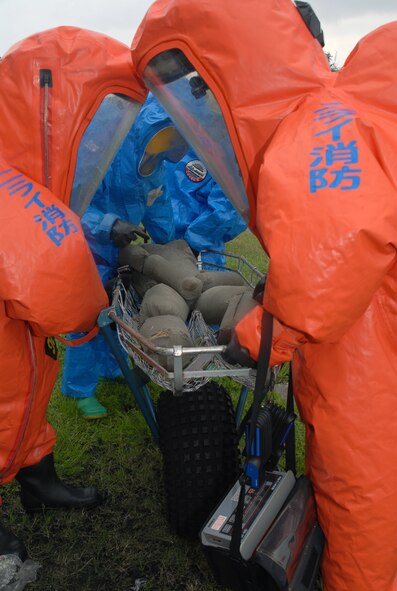 Members of the Kadena Fire Department (wearng the blue hazardous material suit) and the Nirai Fire Department (orange suits),  evacuate a simulated victim during a joint training exercise at Kadena Air Base, Japan, Feb. 14, 2008.  These joint training exercises allow Kadena and Nirai fire department personnel to gain further understanding of each other's skills, and foster a better working relationship. (U.S. Air Force photo/Staff Sgt. Christopher Marasky)
