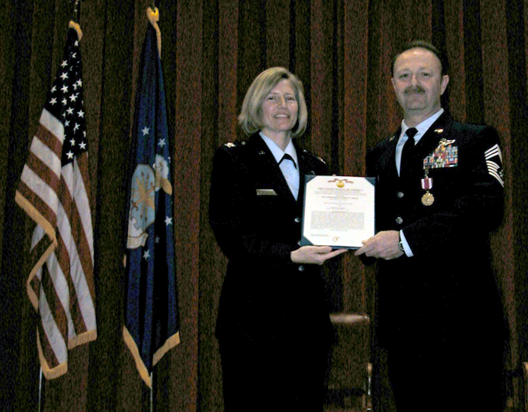 Chief Master Sergeant Robert Dunning stands proudly as he receives the citation accompanying the Air Force Meritorious Service Medal presented by 336th Air Refueling Squadron commander Col. Mary Aldrian during his retirement ceremony at the Cultural Center. The Chief’s Air Force career began in 1977 and included a tour of duty with the 905th Air Refueling Squadron at Grand Forks AFB, North Dakota, and deployments to Saudi Arabia and activation for the Kosovo conflict which lead to him being stationed at Incirlik AB, Turkey. Chief Dunning leaves the 336th ARS as the longest serving chief boom operator in the unit’s history. (U.S. Air Force photo by Staff Sgt. Joseph N. Davidson, 452nd AMW Public Affairs) 