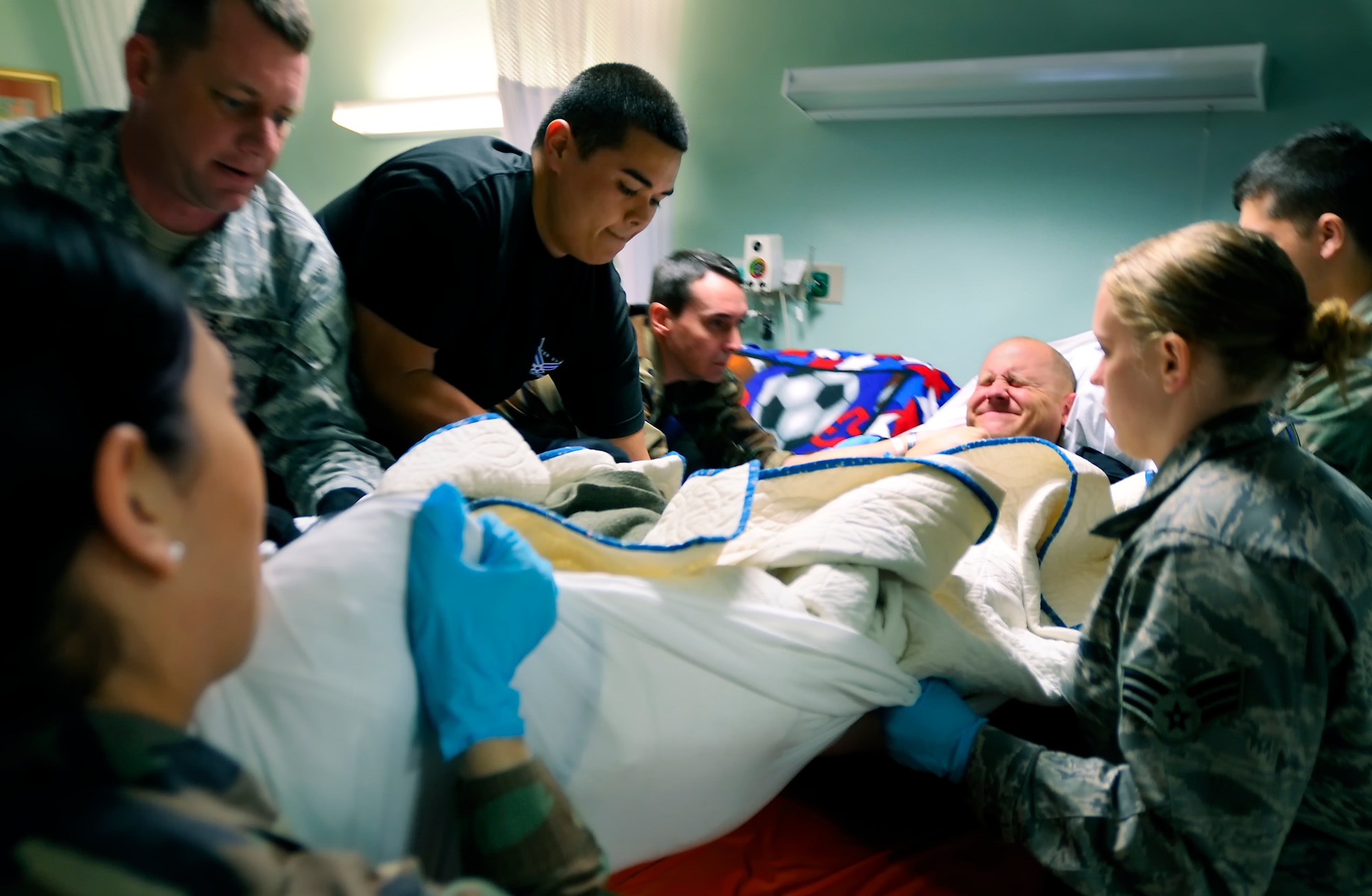 SCOTT AIR FORCE BASE, Ill. -- 375th Aeromedical Staging Facility medical technicians work together to transfer Army Spec. Michael Duer from a litter to a hospital bed Feb. 9 at Scott AFB, Ill. The 375th Airlift Wing located at Scott is one of three ASF distribution hubs in the continental United States that is responsible for transporting patients to their home bases or other specialized hospitals. (U.S. Air Force photo/Master Sgt. Maurice Hessel)