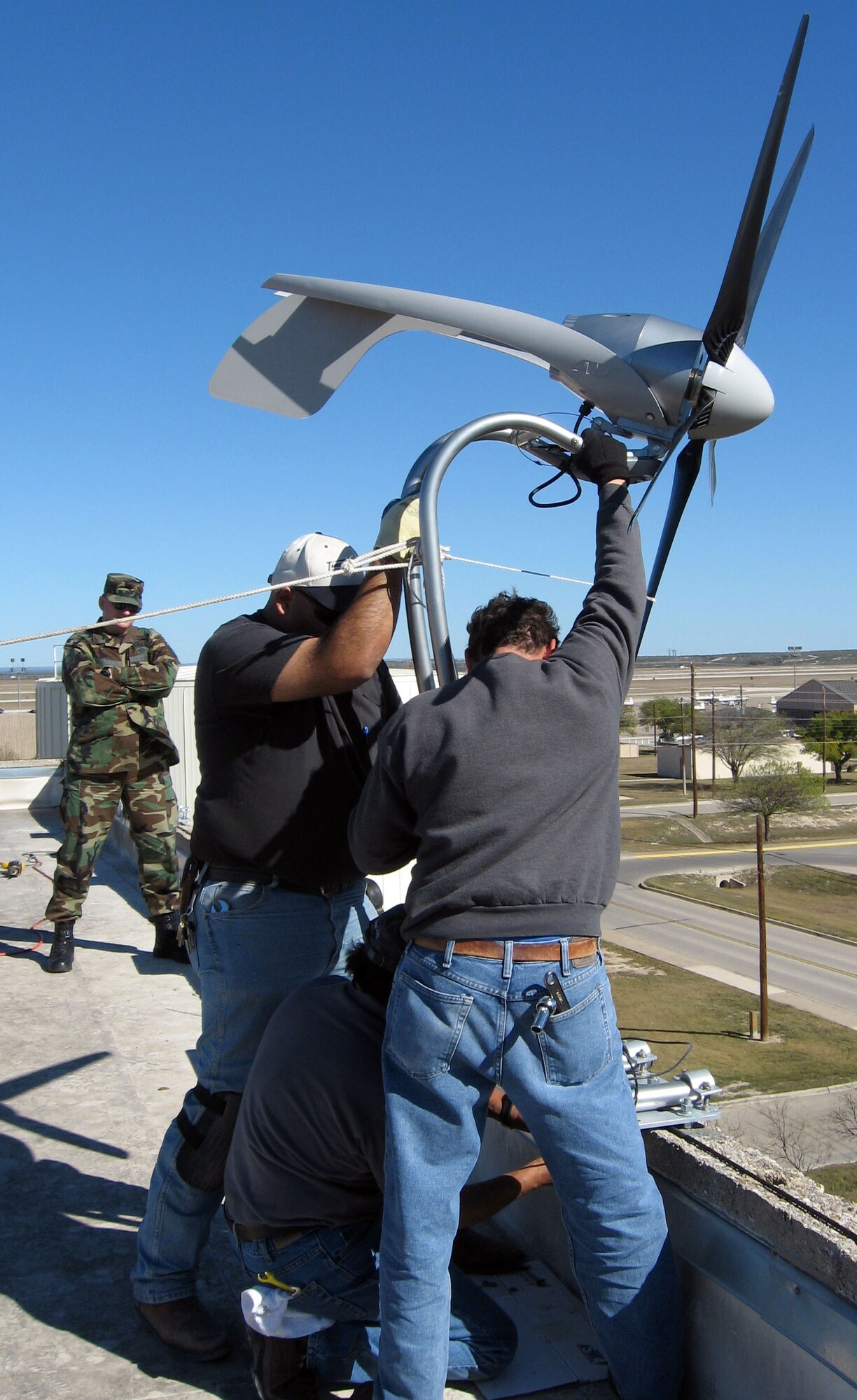 Tech. Sgt. Shawn, 47th Contracting Squadron, observes as contract technicians install one of the first Department of Defense architectural wind-energy system at Laughlin Air Force Base. The project, which started in the summer of 2006 and was completed mid-December of 2007, was driven by the Energy Policy Act and Executive Order 2007-01-24, which requires all bases to strive to have 7.5 percent of renewable energy sources by the year 2013. (U.S. Air Force photo/2nd Lt. Annette Collins)