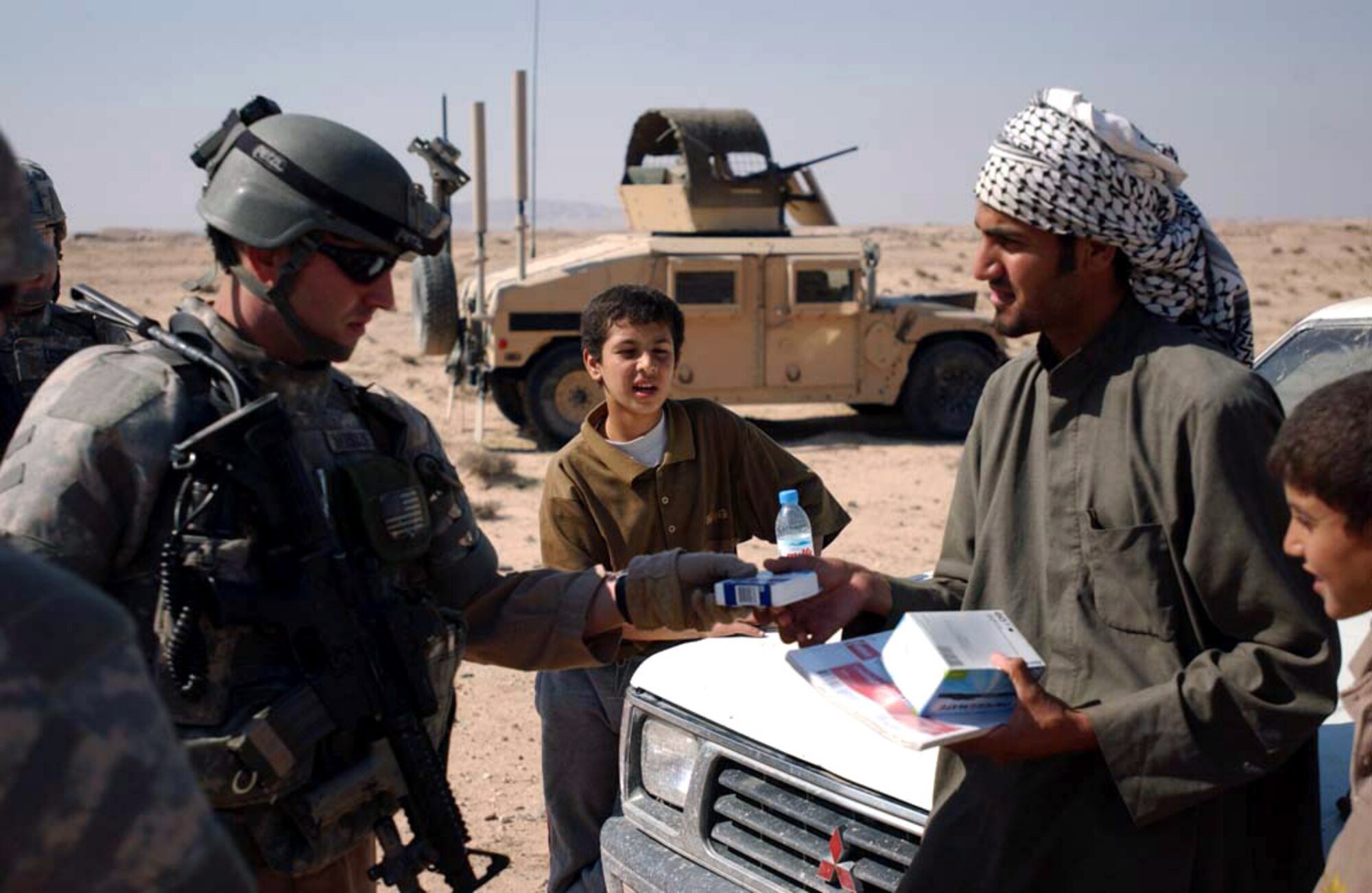 Staff Sgt. Matthew Hamblen distributes schools supplies to an Iraqi man for his younger brothers Feb. 7 near Umm Qasr, Iraq. The donation is part of an area-wide effort around Camp Bucca, Iraq, to aid the surrounding citizens in maintaining their newly returned province. Al-Basra became the ninth province in Iraq to be transitioned to Iraqi provincial control in January. Sergeant Hamblen is deployed from Moody Air Force Base, Ga. (U.S. Army photo/Spc. Brandon Hubbard) 
