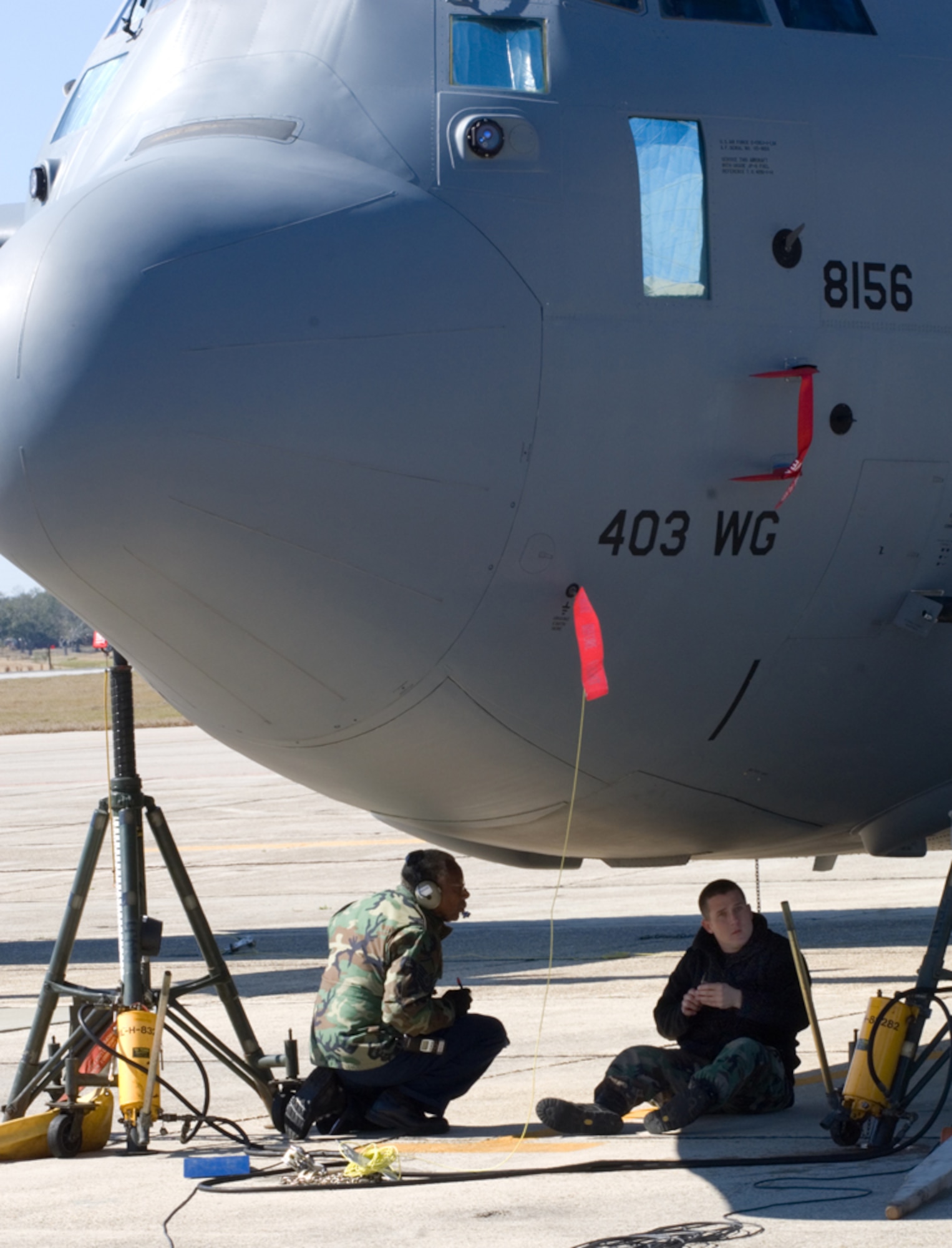 Something may seem amiss to passersby on the Keesler flightline as maintainers, Master Sgt. James Rowe and Staff Sgt. Derek Breland, sit beneath a C-130J-30 that looks as if it has no front landing gear. The two knuckle busters from the 403rd Maintenance Squadron were measuring gaps between the door and the front landing gear compartment.(U.S. Air Force Photo/Tech. Sgt. James B. Pritchett) 