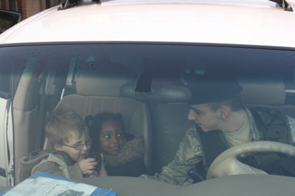 Airman 1st Class Kris Brabaw shows Jasara Goldsborough and Elijah Rushing how to use a police radio during Security Forces demonstration at the Alconbury Child Development Center. 