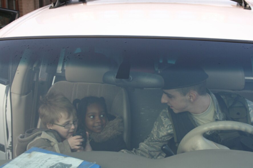 Airman 1st Class Kris Brabaw shows Jasara Goldsborough and Elijah Rushing how to use a police radio during a 423rd Security Forces Squadron demonstration at the Alconbury Child Development Center.