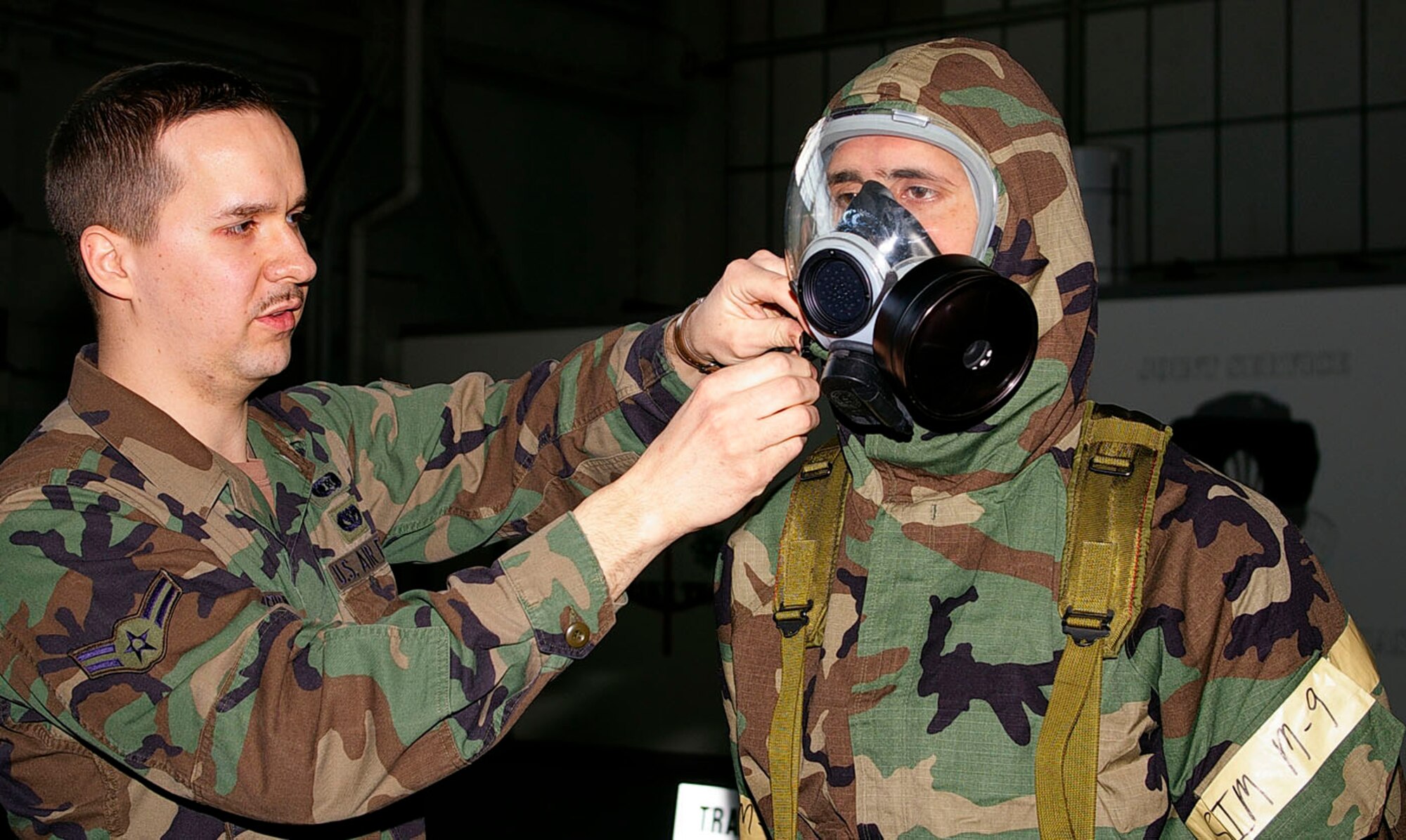 Airman 1st Class Christopher Sherfinski, left, 100th Civil Engineer Squadron Readiness and Emergency Management Flight and CBRN instructor, checks the mask of Senior Airman Christopher Greer, 100th Logistics Readiness Squadron, to make sure it fits properly. All military members are required to have CBRN before they deploy. (U.S. Air Force photo by Karen Abeyasekere)