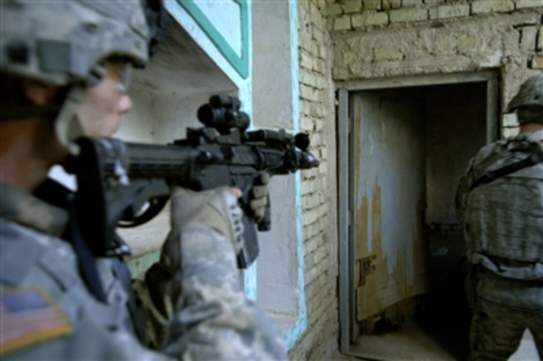 U.S. Army Pvt. Donald Burrow (left) provides over watch security during the breaching and clearing of a room as part of a mission in Sab al Bor, Iraq, on Feb. 10, 2008.  Burrow is assigned to Bravo Troop, 2nd Squadron, 14th Cavalry Regiment, 2nd Stryker Brigade Combat Team, 25th Infantry Division.  