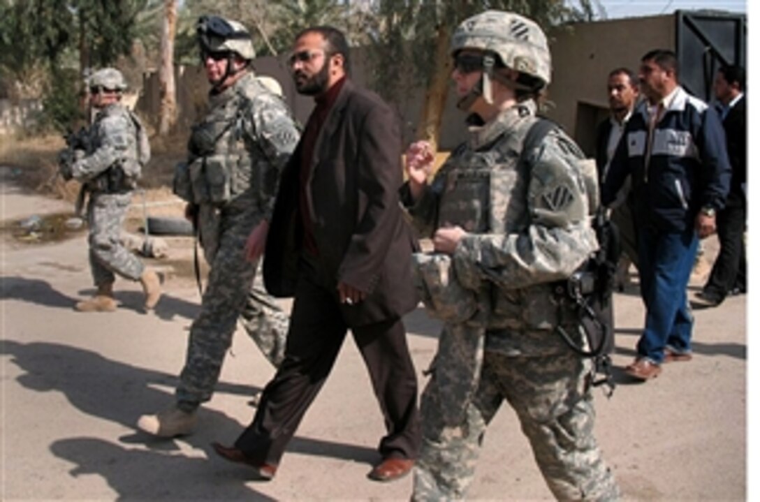 U.S. Army Lt. Col. Ryan Kuhn, Dr. Ihassaan al Jabouri Shwat, health director for the Mada’in Qada, and U.S. Army Maj. Cynthia Majerske walk through the gate of the al Mada’in general hospital in Salman Pak, Feb. 12, 2008. Kuhn, a deputy commander, and Majerske, a surgeon, are assigned to the 3rd Brigade Combat Team.