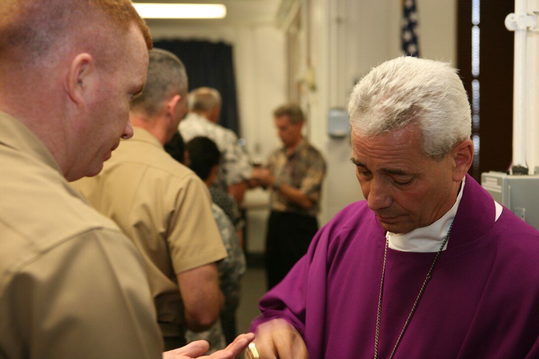 CAMP H.M. SMITH, Hawaii -- Most Reverend Joseph W. Estabrook, D.D., Auxiliary Bishop of the Archdiocese for the Military Services, offers Lt. Col. Andrew Regan communion during Roman Catholic mass, Feb. 15 in the chapel here.  The bishop met with chaplains and some commanders from each service to hear service members' concerns before beginning a Pacific-region tour.  He is scheduled to visit troops and local Roman Catholic churches in Singapore, Okinawa, Guam and Korea.