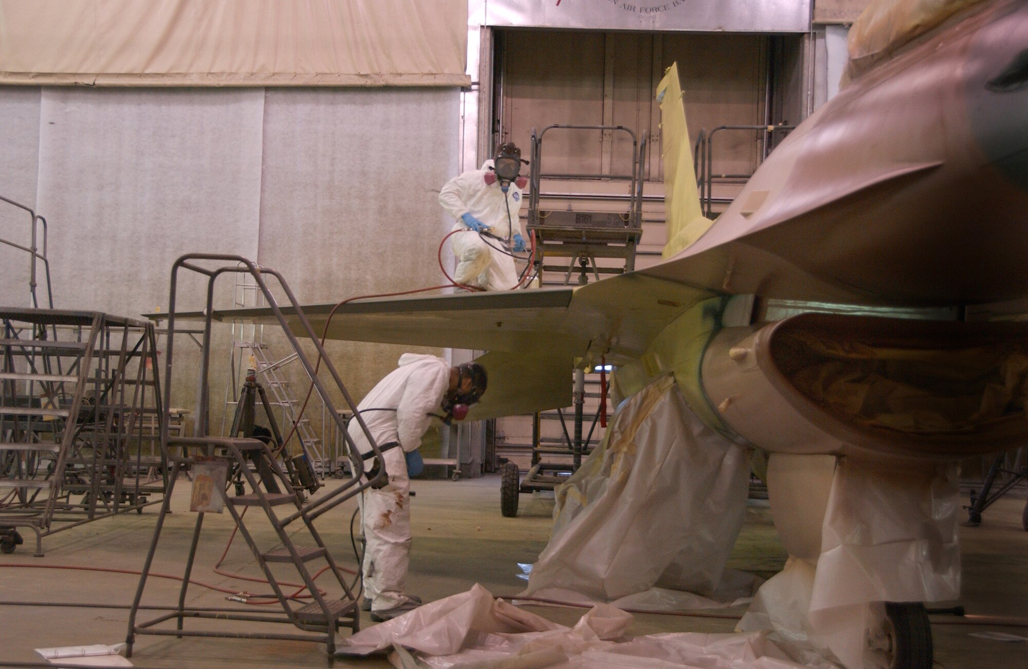 EIELSON AIR FORCE BASE, Alaska --Senior Airman Frank Reardon and Airman 1st Class Eric Rickards, 354th Maintenance Squadron sheet metal workers, apply a jungle theme to an F-16 Feb. 14, 2008, at the corrosion facility. With the swap of the F-16?s from Kunsan to Eielson in support of their new mission as Aggressors each aircraft is applied with a scheme being Arctic Flanker, Blue Flanker or Lizard Flanker, which will stand out from other aircraft that participate in Red Flag-Alaska. (U.S. Air Force photo by Airman 1st Class Christopher Griffin)