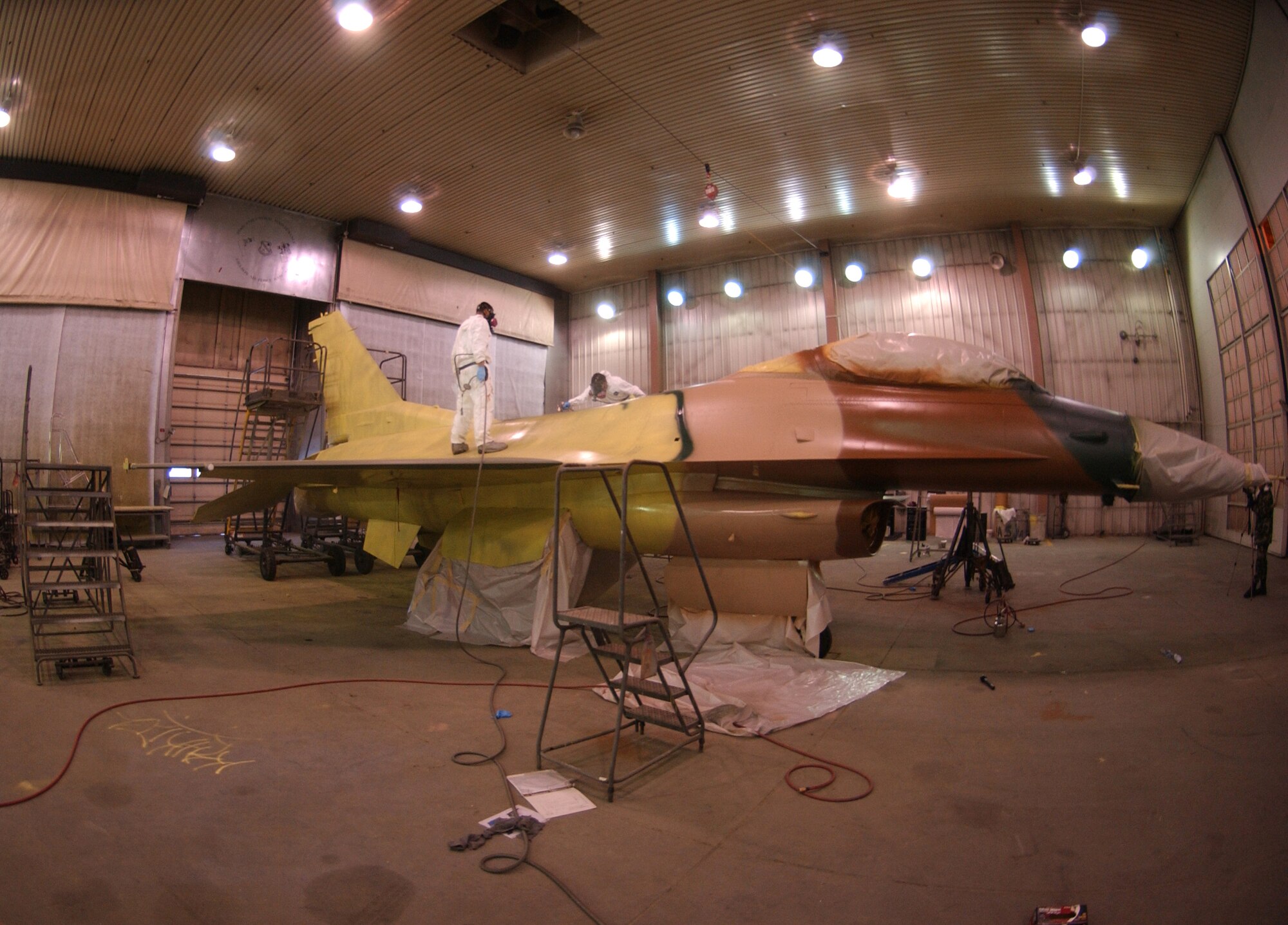 EIELSON AIR FORCE BASE, Alaska -- Senior Airman Frank Reardon and Airman 1st Class Eric Rickards, 354th Maintenance Squadron sheet metal workers, apply a jungle theme to an F-16 Feb. 14, 2008, at the corrosion facility. With the swap of the F-16?s from Kunsan to Eielson in support of their new mission as Aggressors, each aircraft is applied with a scheme being Arctic Flanker, Blue Flanker or a Lizard Flanker. (U.S. Air Force photo by Airman 1st Class Christopher Griffin)