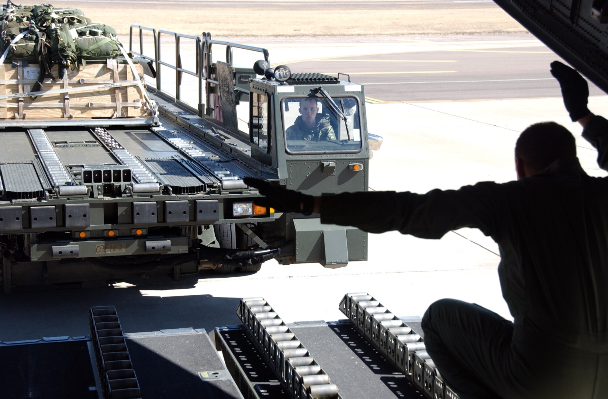 ALTUS AIR FORCE BASE, Okla. -- A loadmaster with the 58th Airlift Squadron here guides in a cargo loading vehicle during a demonstration of the dual row air drop configuration onboard on a C-17 Globemaster III, which was a part of a trade-off study Feb. 12 and 13. Altus AFB servicemembers collaborated with Boeing engineers to find ways to improve the C-17's air drop capabilities. (U.S. Air Force photo/Senior Airman Clinton Atkins).