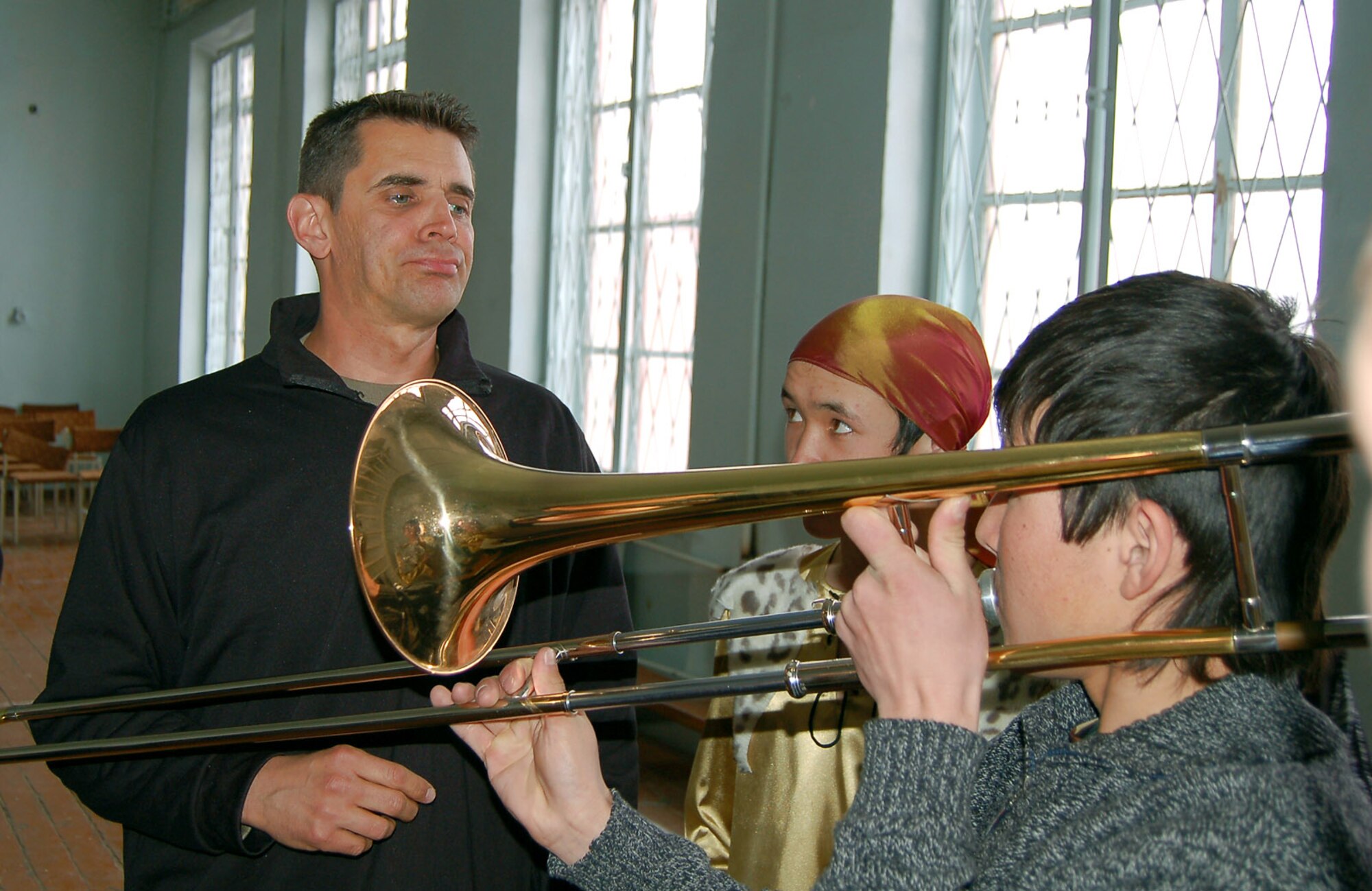Tech. Sgt. Steve Frioux, a trombone player with U.S. Central Command Air Forces Band ?Live Round,? teaches children at the Bishkek Boarding School for the Deaf how to ?buzz? their lips and make sounds with the brass instrument at the school Feb. 13. 'Live Round' performed for Manas Air Base Airmen, and local villages and schools during their eight-day trip to Kyrgyzstan. (U.S. Air Force photo/Senior Master Sgt. Greg Wade)