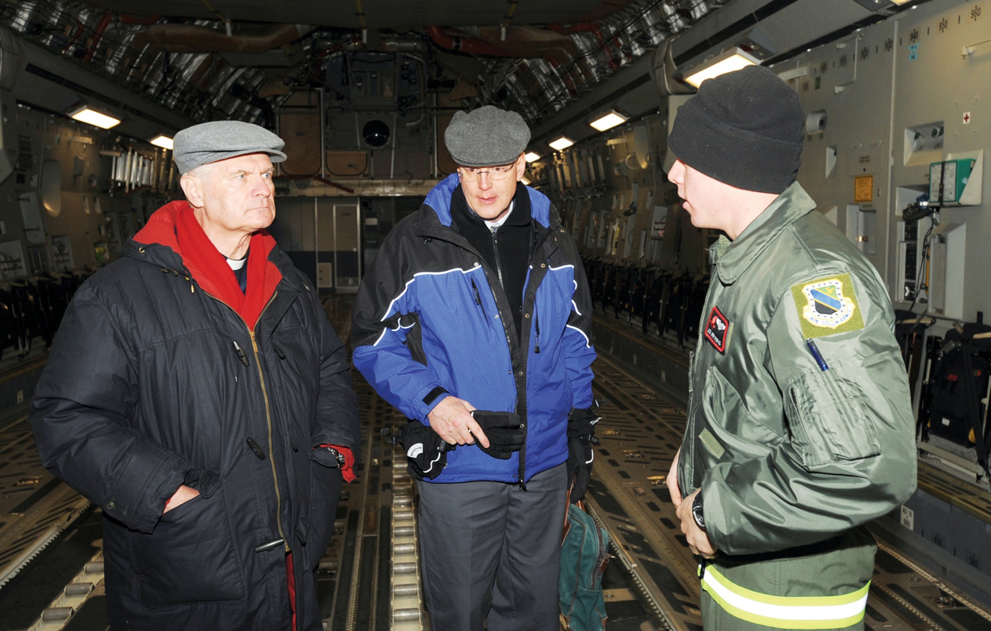 The Most Reverend Roger Schwietz, the Archbishop for the Archdiocese of Anchorage (left), and Brother Craig Bonham, vocational director for the Archdiocese of Anchorage (center), speak with Airman 1st Class Jeffrey Purvis, 517th Airlift Squadron loadmaster, before taking an orientation ride on a C-17 Feb. 4.  (U.S. Air Force photo/Airman 1st Class Matt Owens)