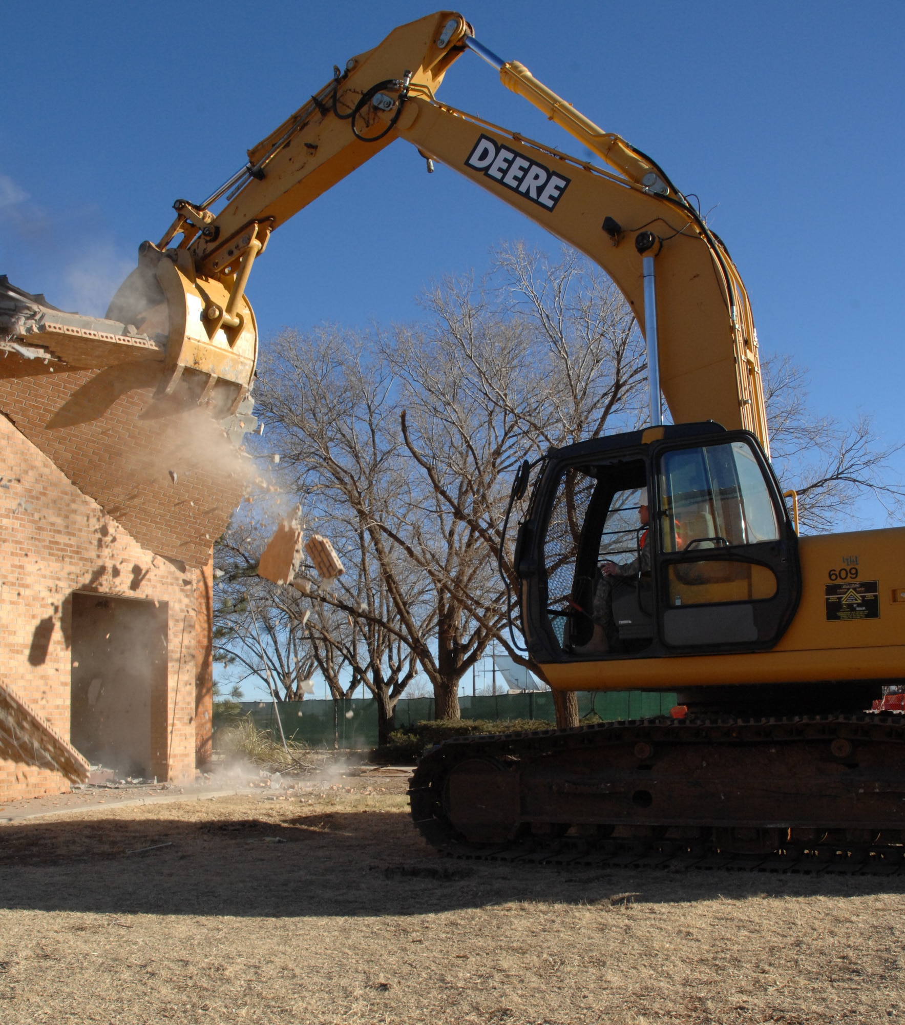 CANNON AIR FORCE BASE, N.M. - Col. Timothy Leahy, 27th Special Operations Wing commander, uses an exavator to remove a chunk of Bldg. 1247 Feb. 13. The building is being demolished to make way for the new Airmen's Center/dining facility. (U.S. Air Force photo by Airman 1st Class Evelyn Chavez)