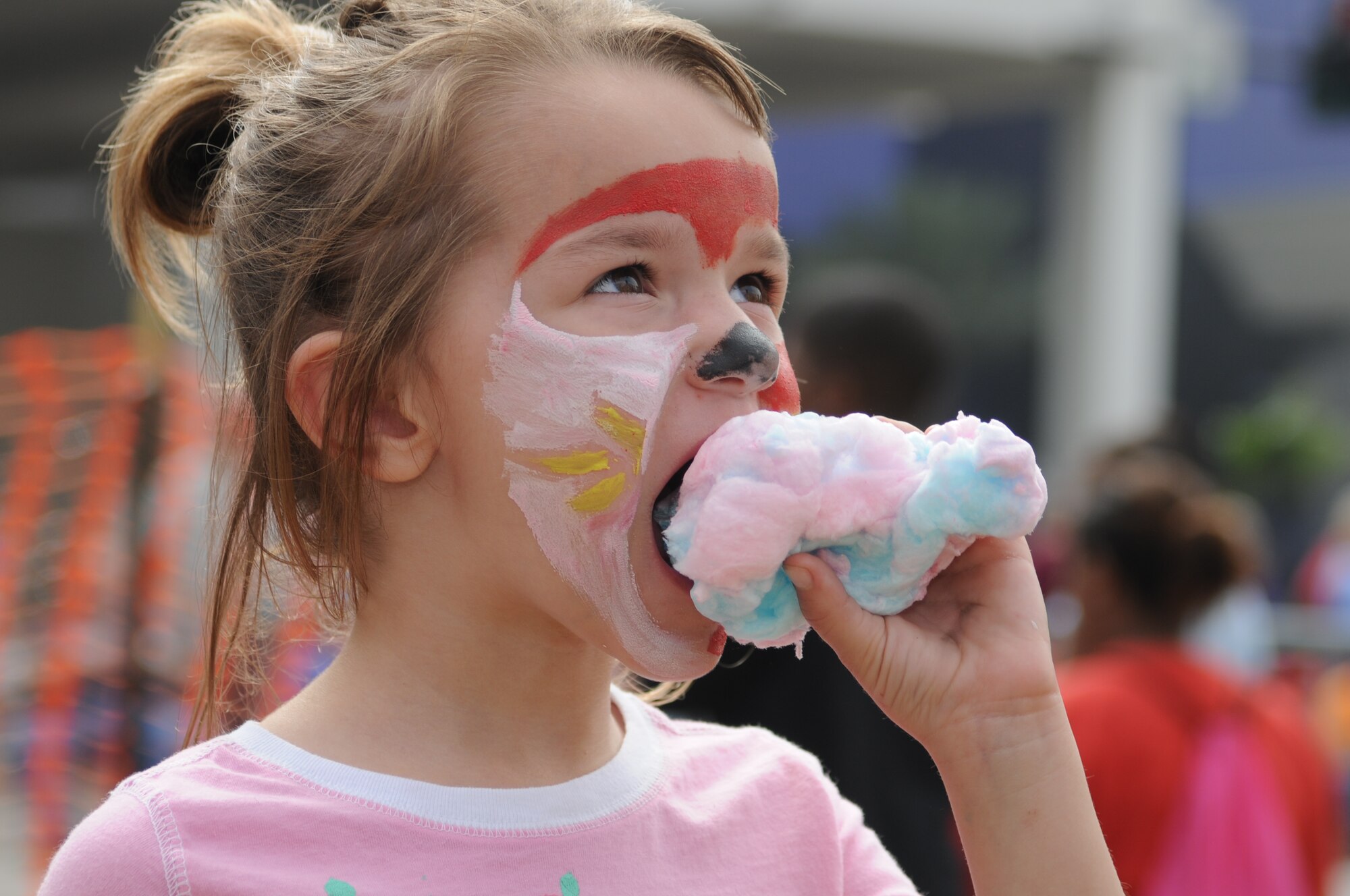 Katie O'Donnell, 4, enjoys cotton candy at the Gulf Coast Carnival Association Mardi Gras Parade Feb. 5.  She was joined by her mom, Georgia.  Her dad, Lt. Col. Matt O'Donnell, 332nd Training Squadron, returns from a one-year deployment to Southwest Asia in May.  The O’Donnells were guests at a party sponsored by the airmen and family readiness center.  (U.S. Air Force photo by Kemberly Groue)