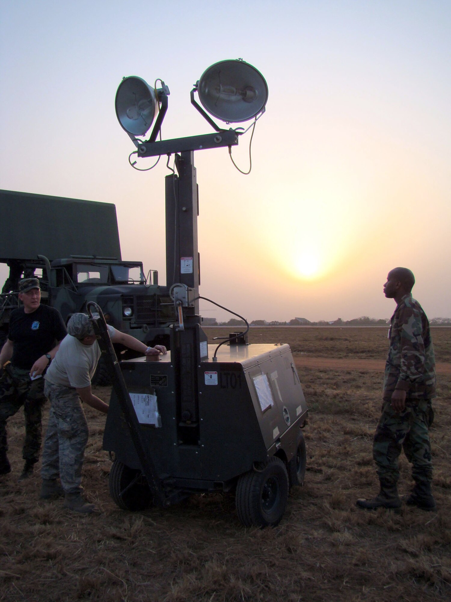Capt. Cheo Stallworth joins Capt. Anthony Lomedico (center) and Tech. Sgt. Gregory Carr as they set up an FL-1D lightall Feb. 13 in Accra, Ghana. The mobile lighting unit will be used during night operations on the airstrip in Accra. The Airmen are members of a multiservice team who have deployed to the African continent to providing support for President George Bush's five-nation visit. Captain Stallworth is assigned to the 1st Combat Communications Squadron at Ramstein Air Base, Germany, Captain Lomedico is an airspace battle manager, and Sergeant Carr is a satellite communications technician. Captain Lomedico and Sergeant Carr are both from the 603rd Air Control Squadron at Aviano AB, Italy. (U.S. Air Force photo/Tech. Sgt. Denise Johnson) 
