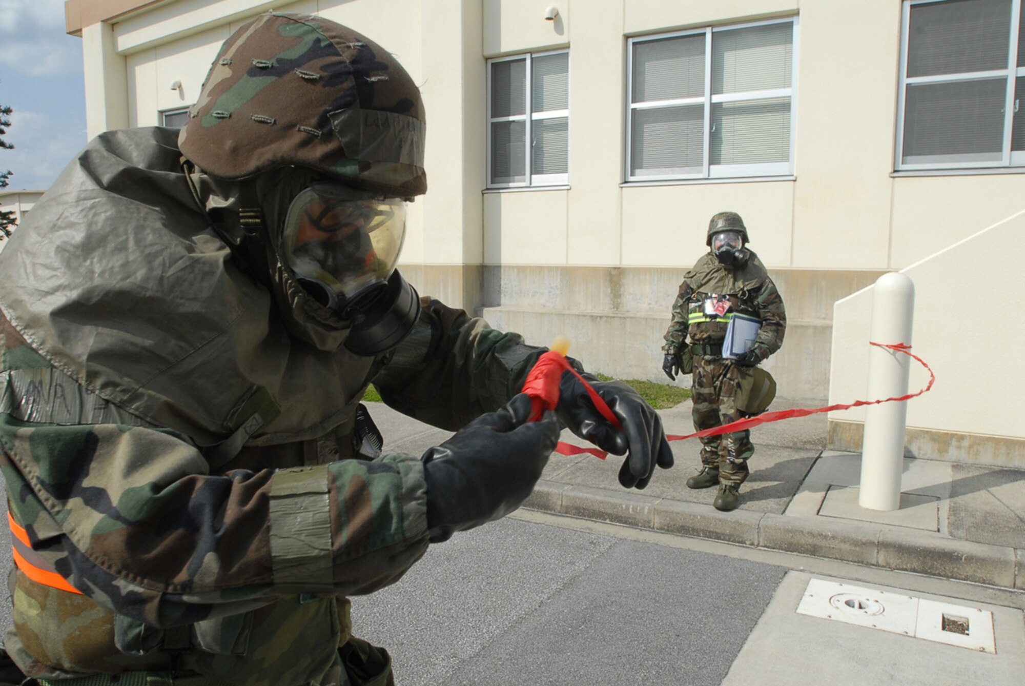 Senior Airman Samuel Wager, 961st Airborne Air Control Squadron, uses tape to mark the perimeter of a simulated unexploded ordinance while Exercise Evaluation Team Member Capt. Rodney Lammert evaluates during local operational readiness exercise Beverly High 08-4 at Kadena Air Base, Japan, Feb. 15, 2008. The 18th Wing conducted the exercise from Feb. 10 to 15 to test Airmen's ability to respond in contingency situations. (U.S. Air Force photo/Senior Airman Darnell T. Cannady) 