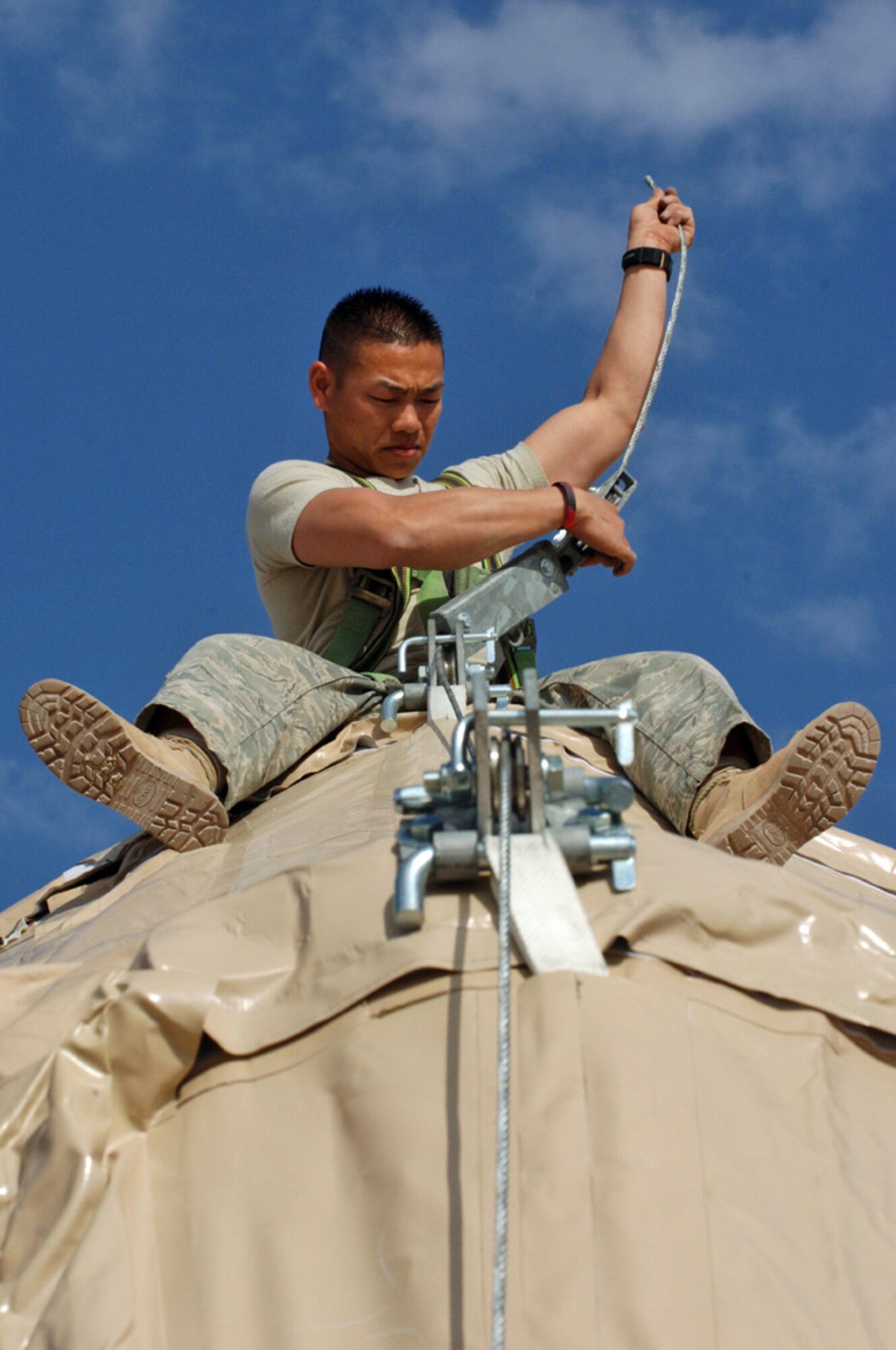 ALI BASE, Iraq -- Tech. Sgt Sangva Sam of the 407th Expeditionary Civil Engineering Squadron runs cable on top of a Dome shelter at the Alpha site Feb 14.   TSgt Sam is deployed from Eielson AFB, Alaska. (U.S. Air Force photo by Tech. Sgt. Sabrina Johnson)