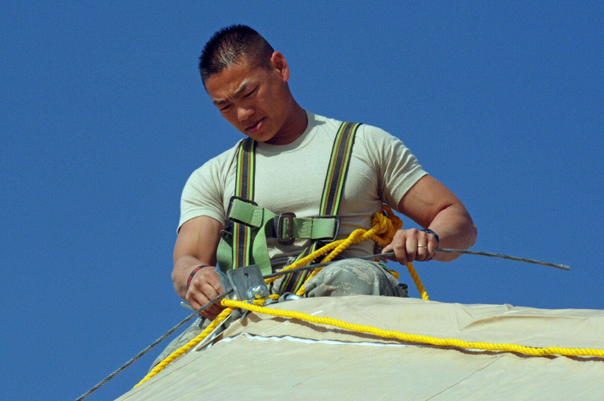 ALI BASE, Iraq -- Tech. Sgt. Sangva Sam, 407th Expeditionary Civil Engineering Squadron runs cable on top of a Dome shelter at the Alpha site Feb 14. Tech. Sgt. Sam is deployed from Eielson AFB, Alaska. (U.S. Air Force photo by Tech. Sgt. Sabrina Johnson)