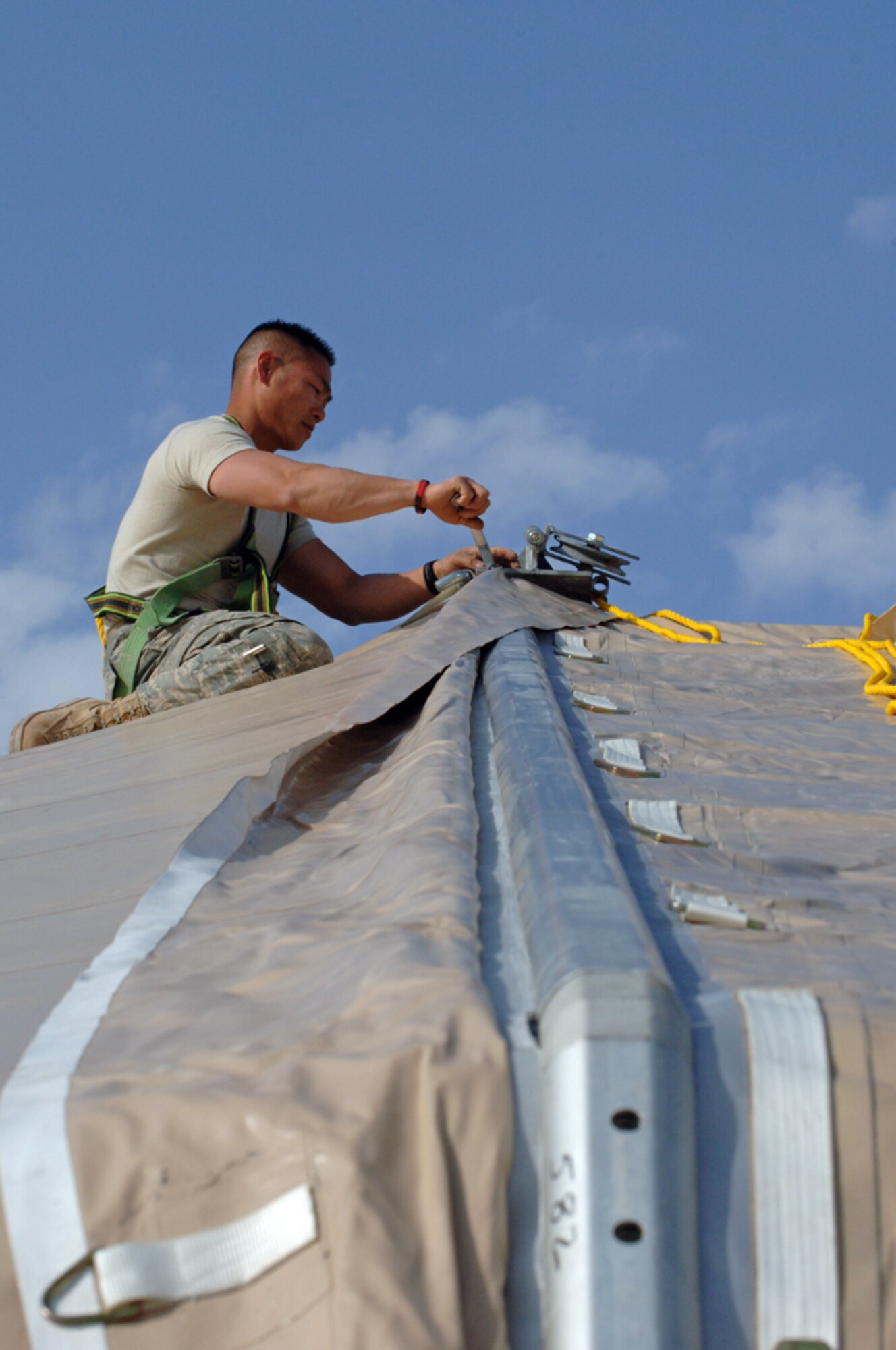 ALI BASE, Iraq -- Tech. Sgt. Sangva Sam, 407th Expeditionary Civil Engineering Squadron runs cable on top of a Dome shelter at the Alpha site Feb 14. Tech. Sgt. Sam is deployed from Eielson AFB, Alaska. (U.S. Air Force photo by Tech. Sgt. Sabrina Johnson)