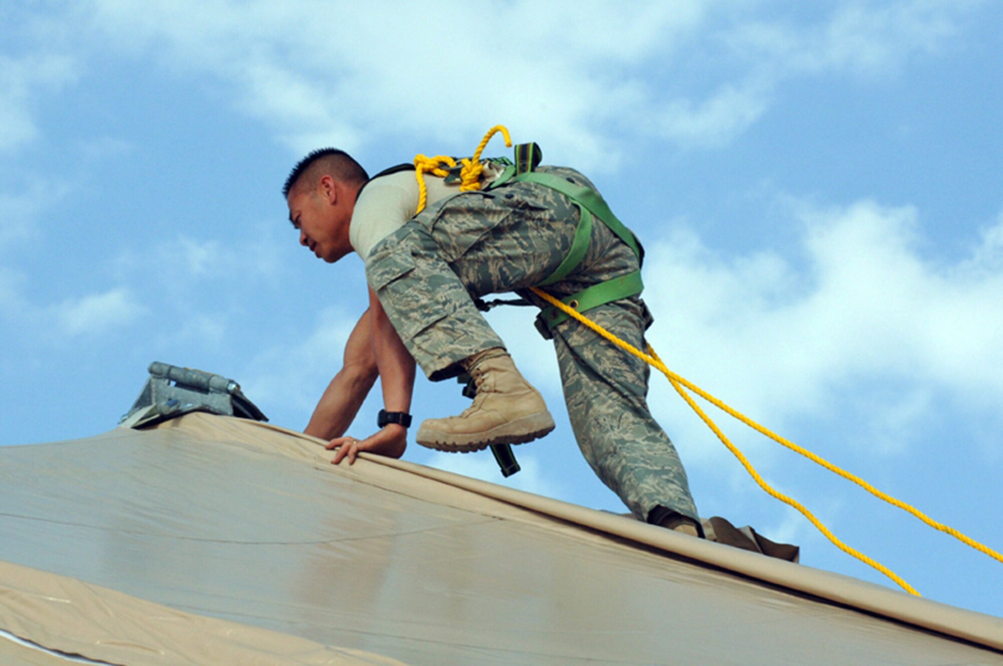 ALI BASE, Iraq -- Tech. Sgt. Sangva Sam, 407th Expeditionary Civil Engineering Squadron climbs on top of a Dome shelter to run cables at the Alpha site Feb 14. Tech. Sgt. Sam is deployed from Eielson AFB, Alaska. (U.S. Air Force photo by Tech. Sgt. Sabrina Johnson)