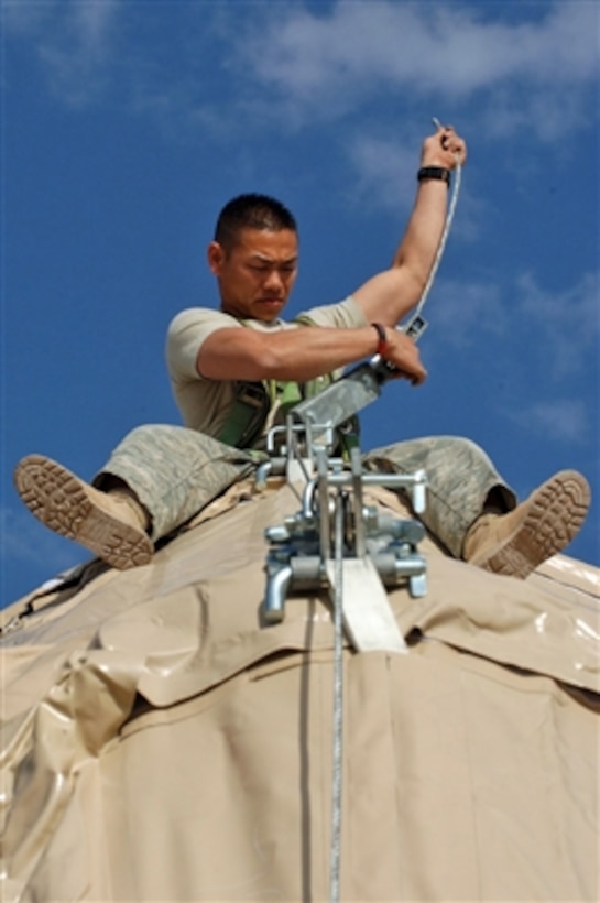 U.S. Air Force Tech. Sgt. Sangva Sam runs a cable on the top of a dome shelter on Ali Air Base, Iraq, on Feb. 14, 2008.  Sam and his fellow airmen from the Air Force's 407th Expeditionary Civil Engineering Squadron are erecting the temporary shelters on Ali Air Base.  
