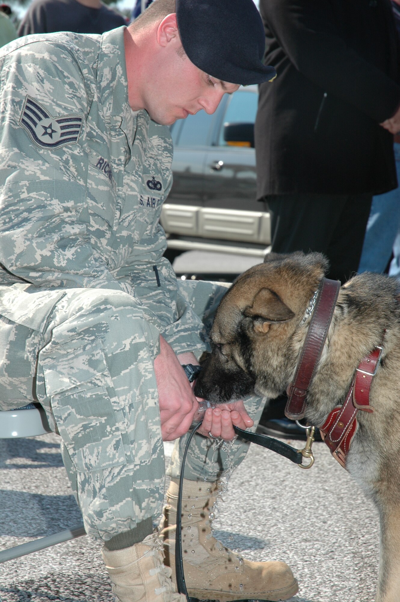 Staff Sgt. James Richey, 96th Security Forces Squadron military working dog handler, gives Baddy, his partner of 2 years, much needed refreshment during the ceremony.  (USAF phot/Staff Sgt. Stacia Zachary)
