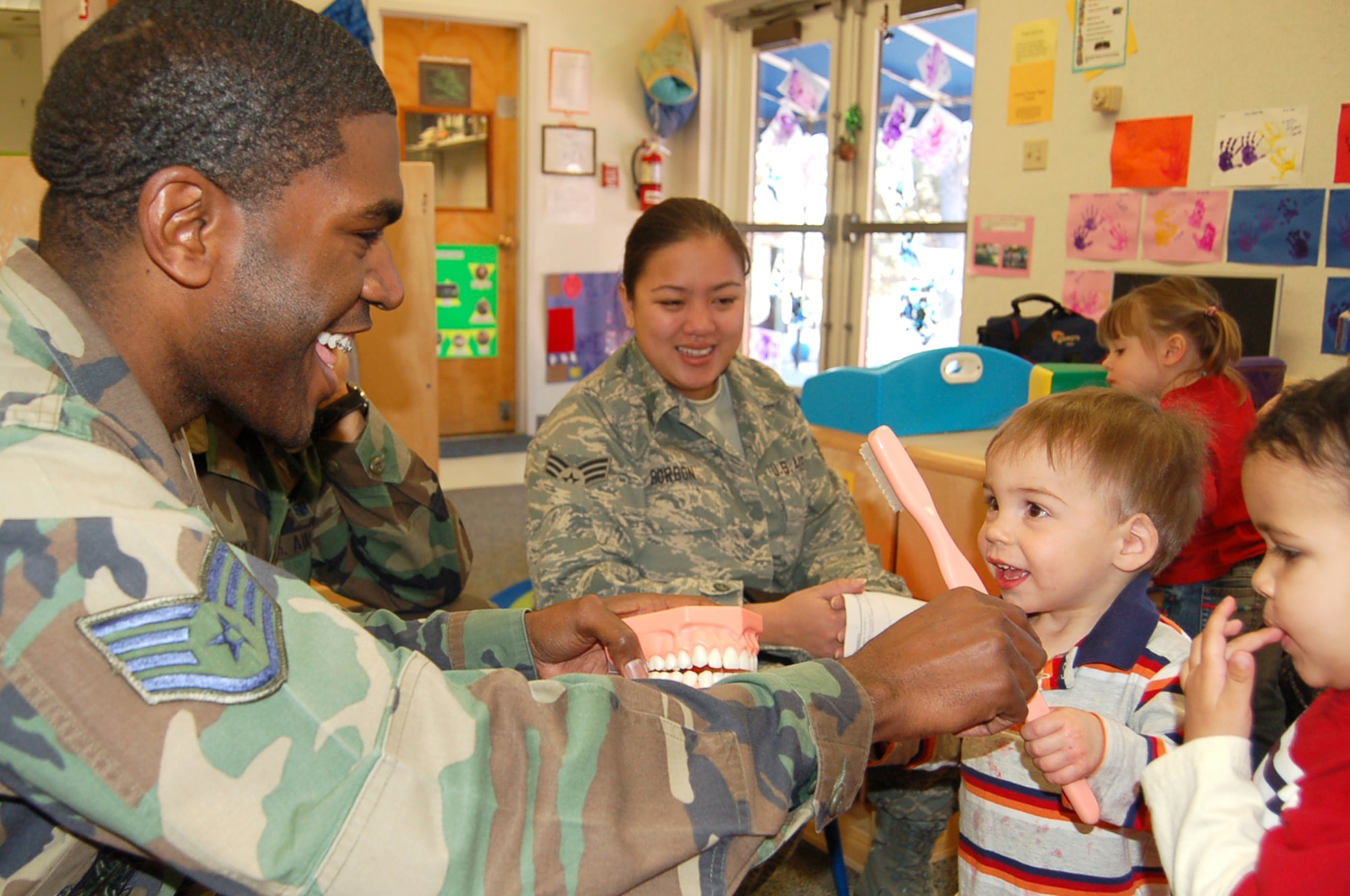 Staff Sgt. Jason Atkins and Senior Airman Marifel Borbon (back)  talk to toddlers about dental health at the Peterson Child Development Center Annex Feb. 13. Members of the 21st Dental Squadron are visiting the CDC, the R.P. Lee Youth Center and local elementary schools this month as part of National Children’s Dental Health Month. (U.S. Air Force photo/Corey Dahl)