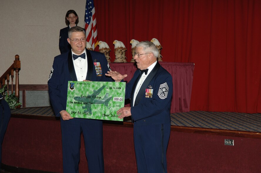 FAIRCHILD AIR FORCE BASE, Wash. -- Chief Master Sgt. Paul Sikora, 92nd Air Refueling Wing command chief, presents a mock check to Chief Master Sgt. Robert Gaylor (ret.), fifth Chief Master Sgt. of the Air Force, made out to the Enlisted Village during the 2007 Annual Awards Banquet at Club Fairchild Feb. 15. Enlisted Village is an assisted living community for spouses of Air Force retirees who need a home. (U.S. Air Force photo / Senior Airman Jocelyn Ford)