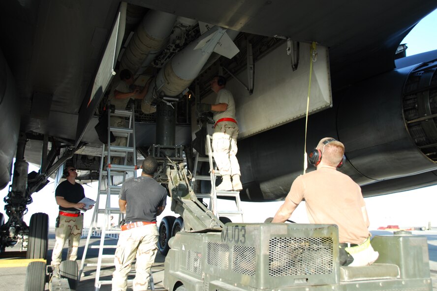 SOUTHWEST ASIA -- A Weapons Load Crew with the 379th Expeditionary Aircraft Maintenance Squadron at a Southwest Asia air base, loads two-thousand pound bombs onto a B-1B Lancer to prepare it for a mission. Airman David Pownell drives the ram jammer while Staff Sgt. Brandon Neitz (left) and Technical Sgt. James Sheldon (right) attach the bomb to the conventional rotary launcher inside the bomb bay of the aircraft. (United States Air Force photo by Staff Sergeant Douglas C. Olsen)