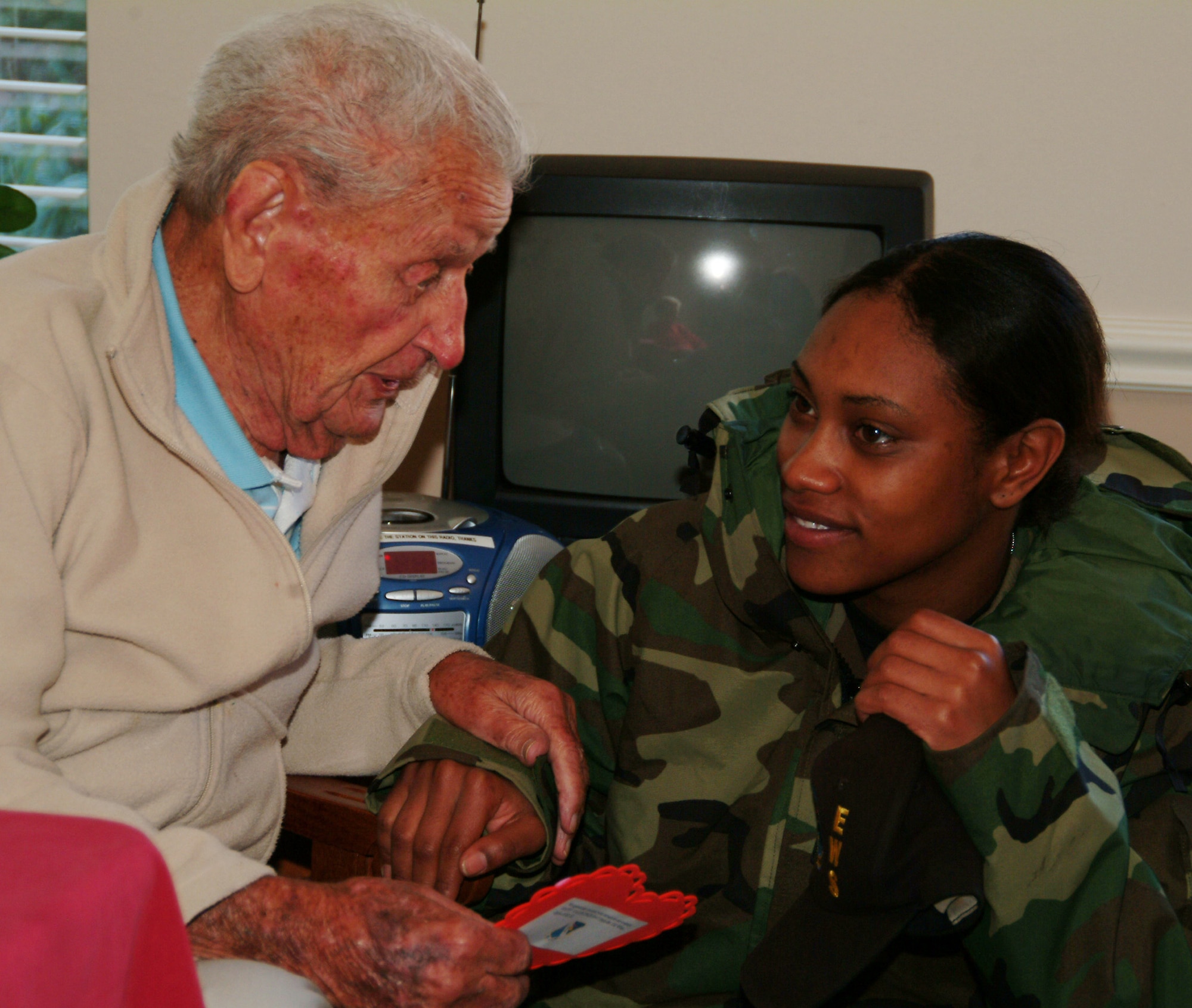 Senior Airman Dietta Morris, 68th Electronic Warfare Squadron, listens to George, a 99-year-old Army veteran, Feb. 14 at the Sterling House in Niceville Fla.  More than 50 active duty 53d Wing members presented vets in nursing homes around the local area with cards and candy on Valentine's Day.  U.S. Air Force photo by Master Sgt. Andrew Leonhard.  
