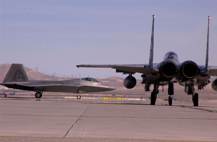 NELLIS AIR FORCE BASE, Nev.—An F-15S from the Royal Saudi air force waits for an F-22 Raptor from the 1st Fighter Wing, Langley AFB, Va., to taxi onto the runway during Red Flag exercise 08-2.2 here Feb. 12. Red Flag is a multi-national exercise providing pilots with a realistic environment to practice combat scenarios. The experience gained during Red Flag is vital to the survival of pilots in combat. (U.S. Air Force photo by Airman 1st Class Ryan Whitney)