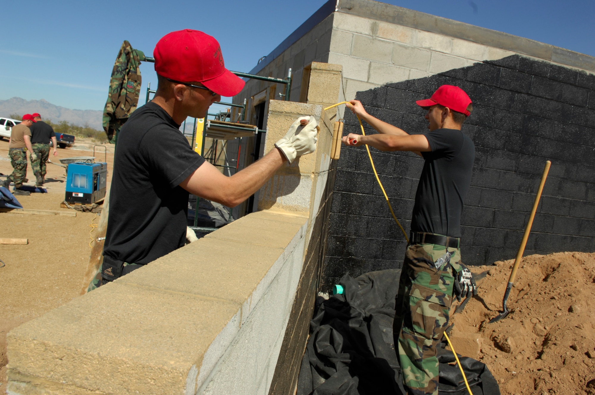 Senior Airman Jason Holmlund, left, and Staff Sgt. Jason White, both 219th RED HORSE Squadron members, paint a wall desert tan for the new Explosive Ordinance Disposal range bunker Feb. 11. Airman Holmlund and Sergeant White are two of 17 RED HORSE members TDY here from Malmstrom Air Force Base, Mont. The Guardsmen are here to build a new range bunker for the 355th Civil Engineer EOD shop. (U.S. Air Force photo by Senior Airman Jesse Shipps)