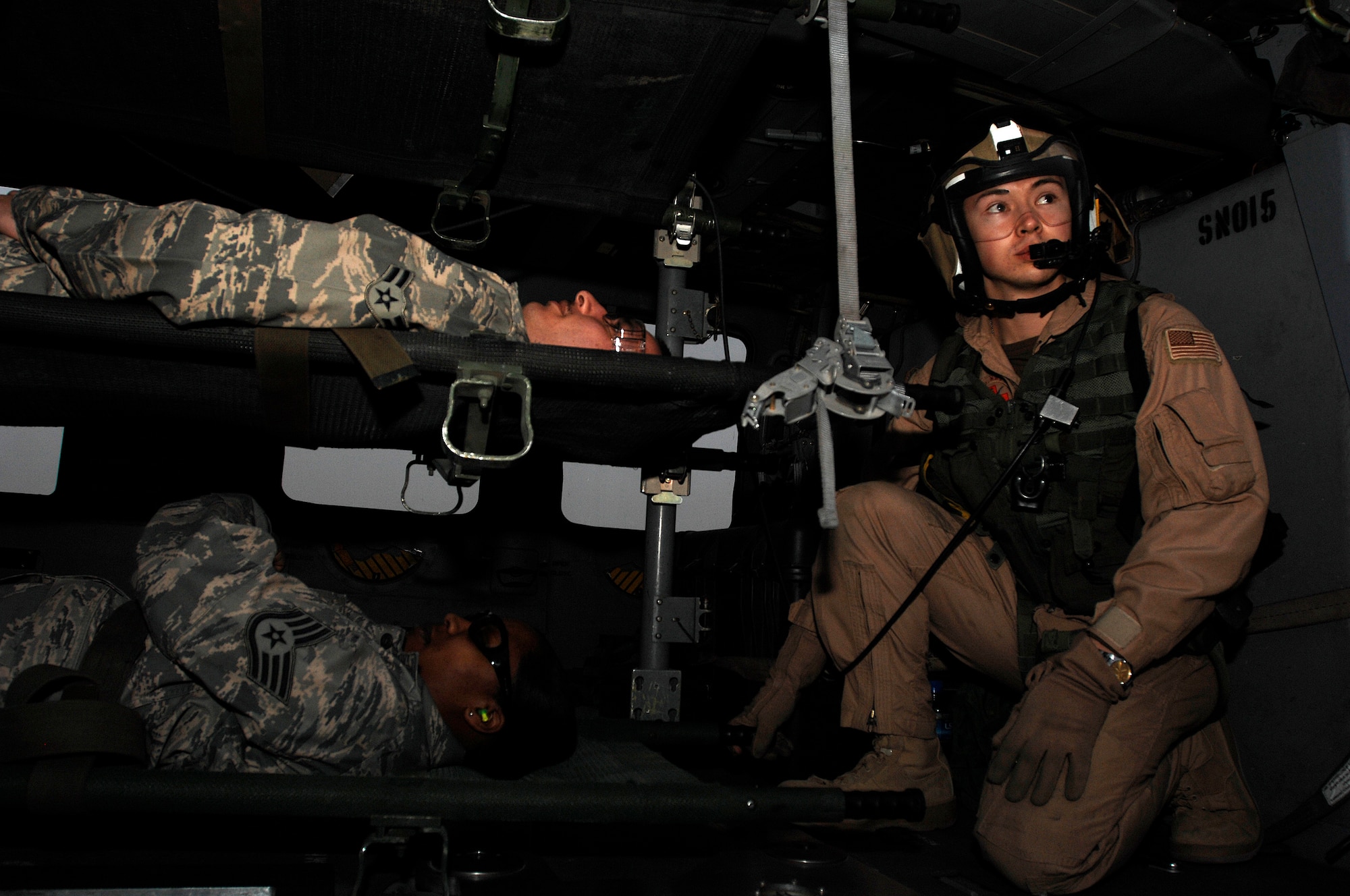 SOUTHWEST ASIA -- U.S. Navy Aviation Warfare Specialists 3rd Class (AW3) Eric Uhden (right) gazes out while Airman 1st Class Edward Cuza and Staff Sgt. Siobahn Simon, members from the 386th Expeditionary Medical Group, wait to be extracted from a U.S. Navy MH-60 Sierra helicopter during litter management system training at an air base in the Persian Gulf Region Feb. 18, 2008. The training familiarizes medical personnel on the loading and extracting techniques of patients for medical evacuation missions in support of Operations Enduring and Iraqi Freedom.  (U.S. Air Force photo/ Staff Sgt. Patrick Dixon)  